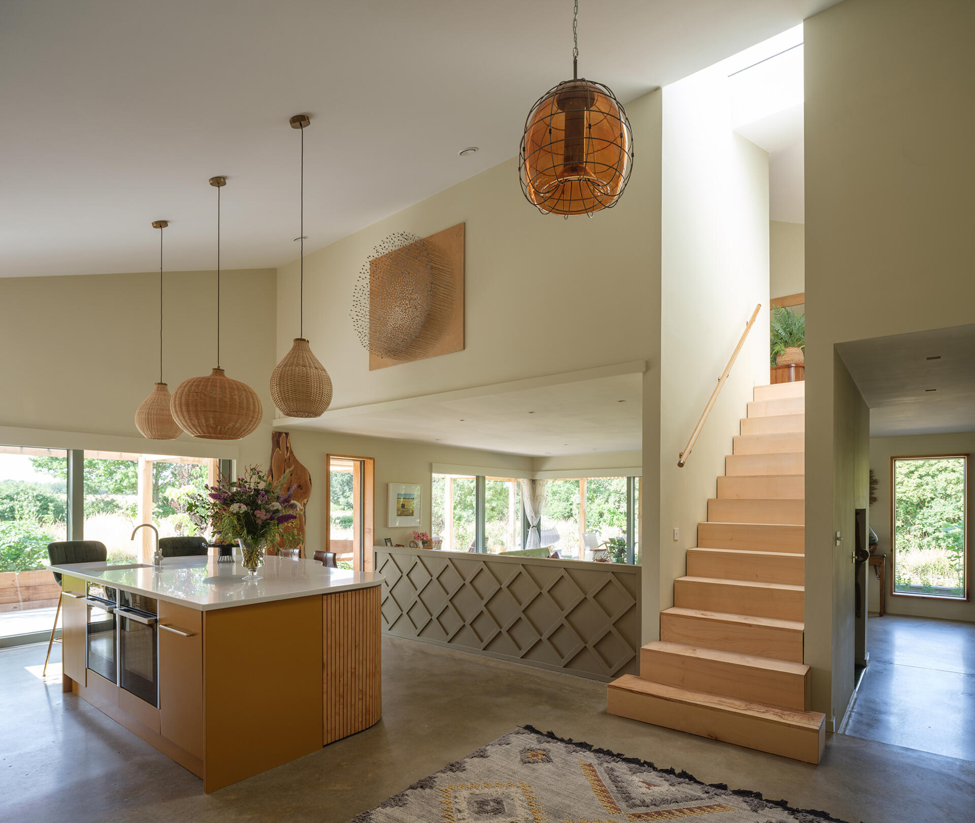 The wood staircase is integrated into the compact footprint, designed to move efficiently between levels without interrupting the flow of the main spaces. 