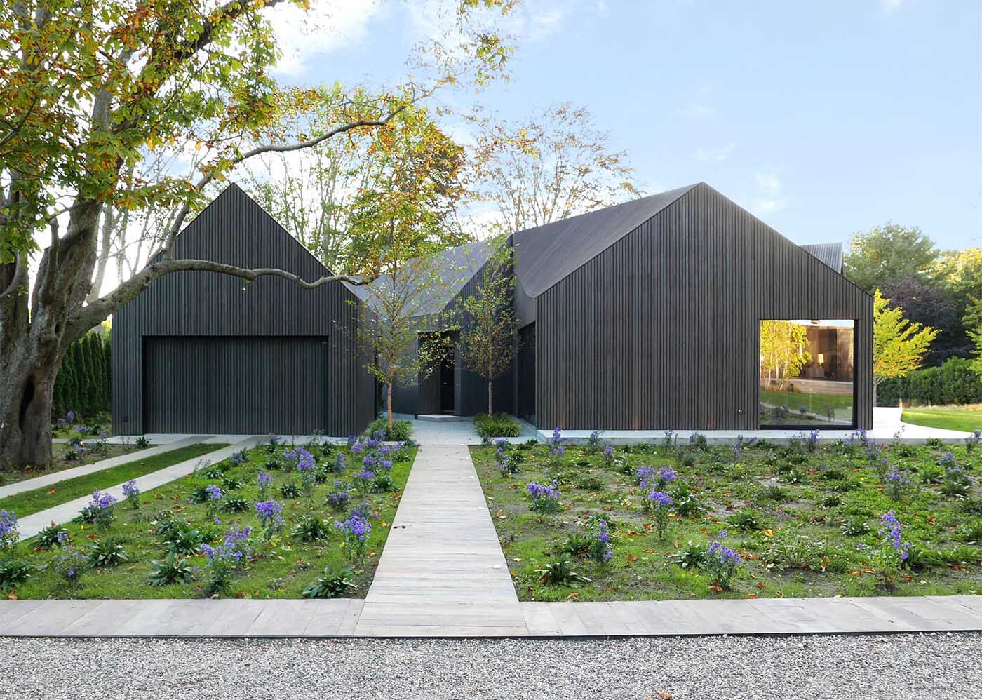 Deep gray Accoya wood cladding gives this modern home a bold exterior, with textured slats that highlight its sculptural roofline.