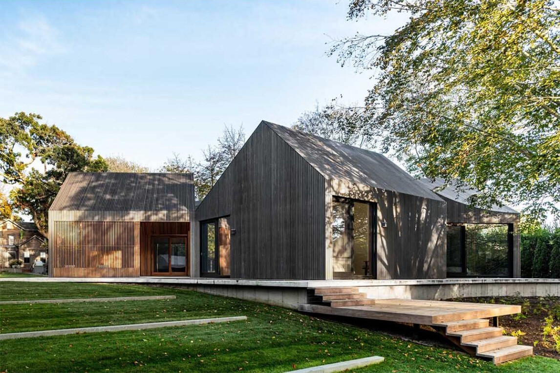 Deep gray Accoya wood cladding gives this modern home a bold exterior, with textured slats that highlight its sculptural roofline.