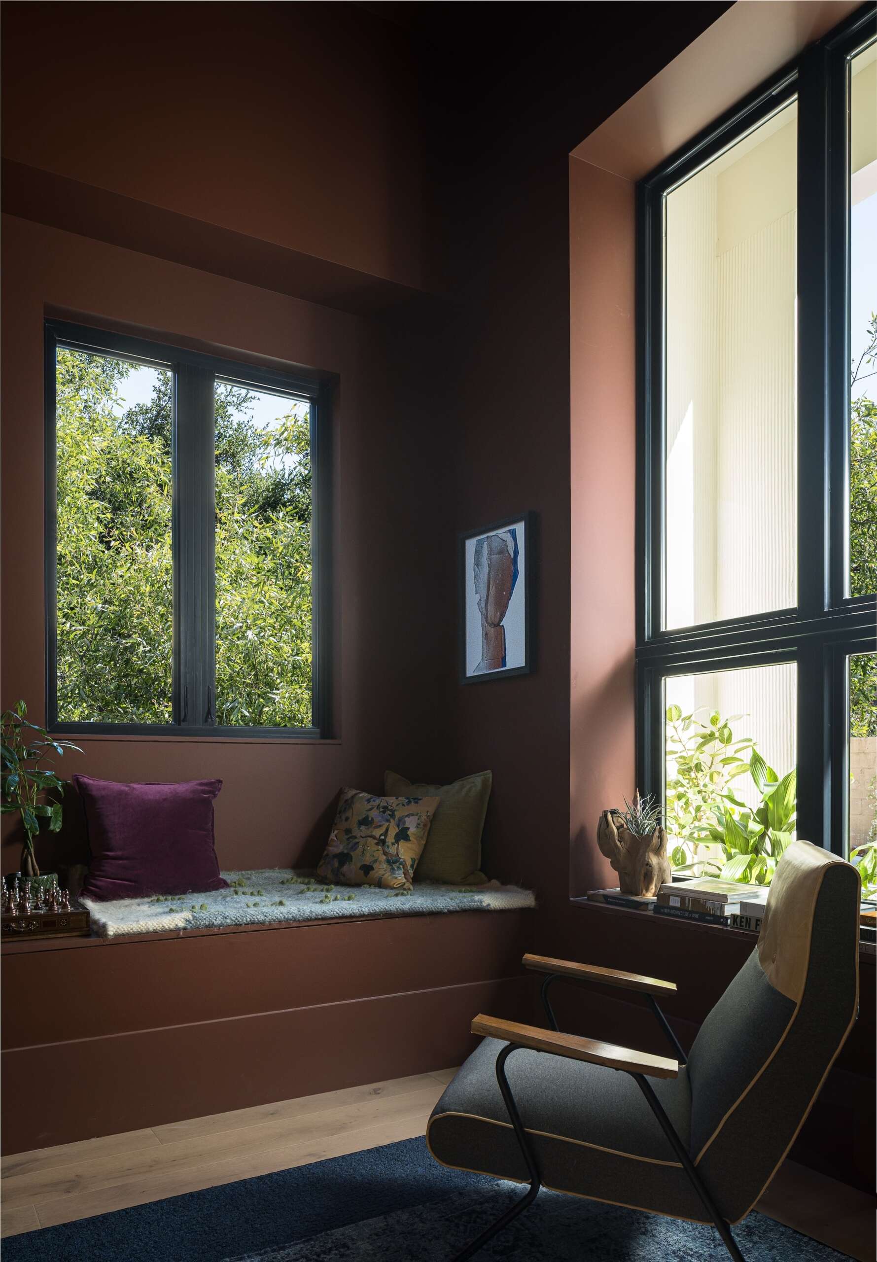 The library, with its deep brown walls, offers a different atmosphere. With its double-height volume and a bay-window reading nook, it provides a place set apart from the more active areas of the house.