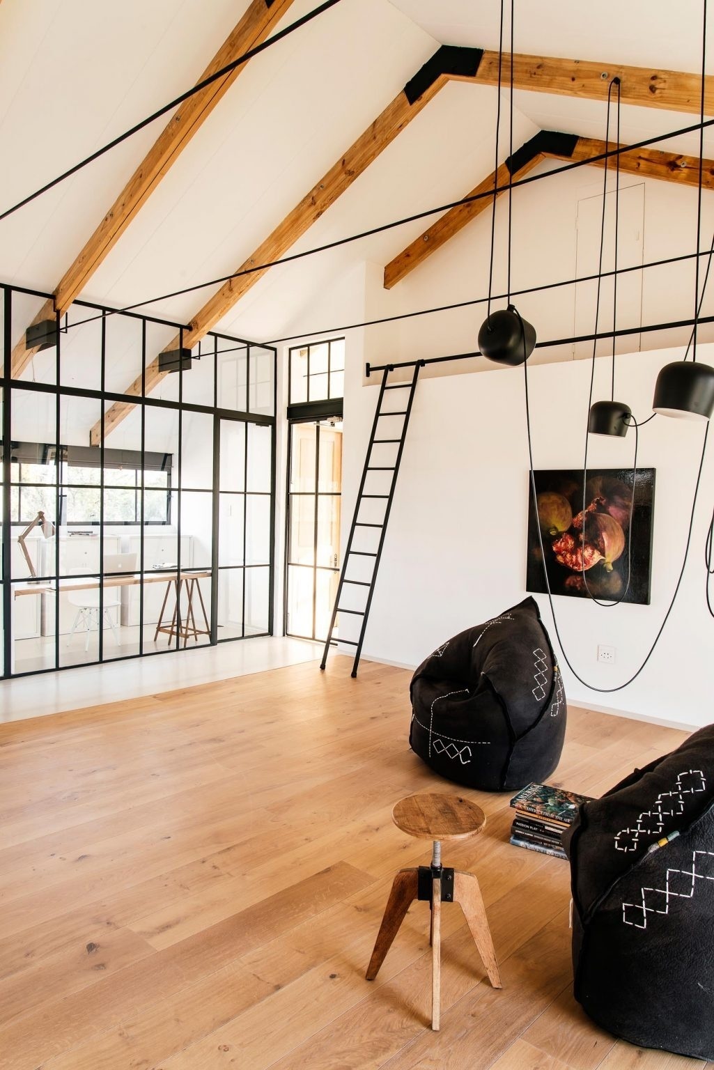 Exposed beams, wood floors, and black felt chairs bring warmth and texture into the living space.