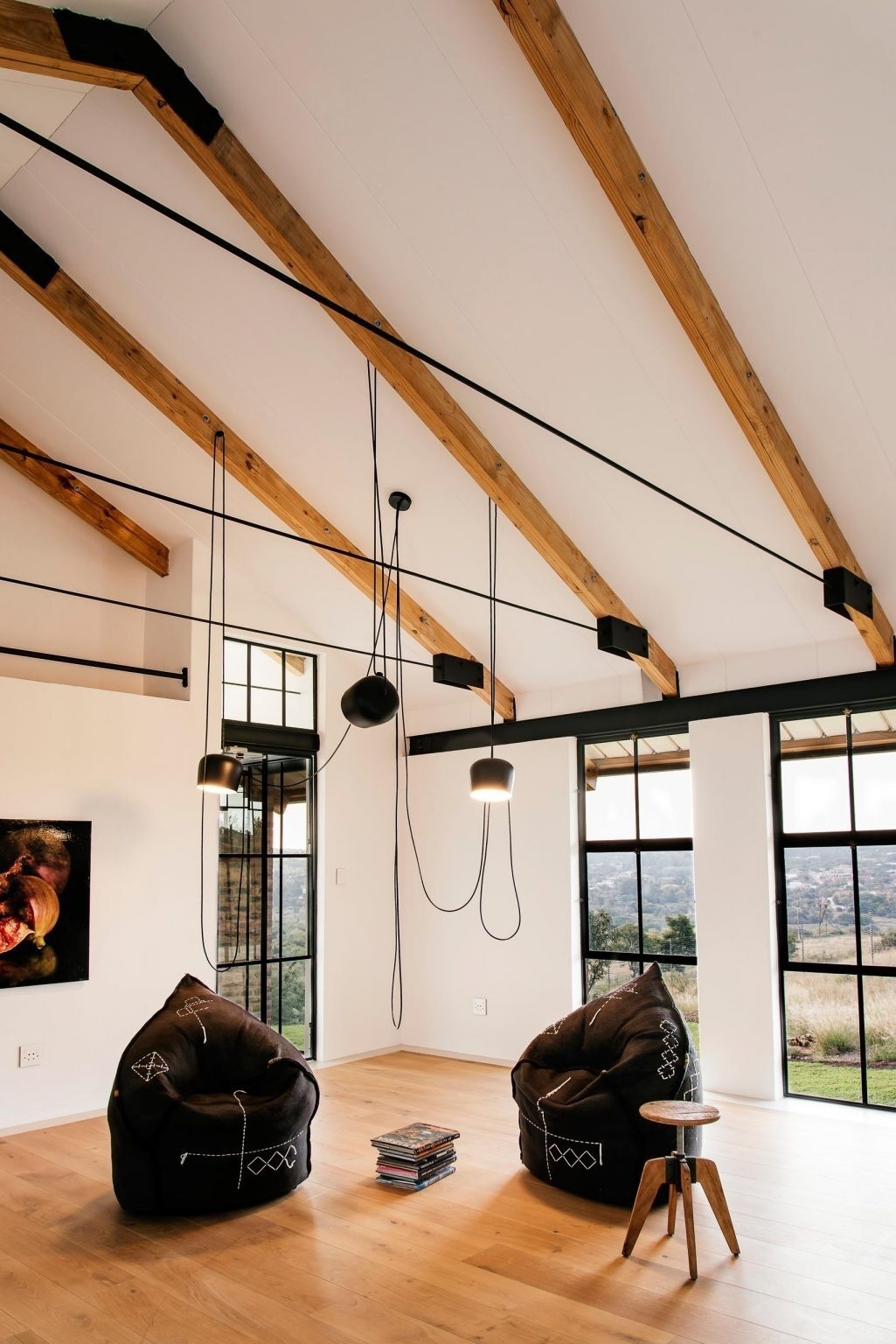 Exposed beams, wood floors, and black felt chairs bring warmth and texture into the living space.
