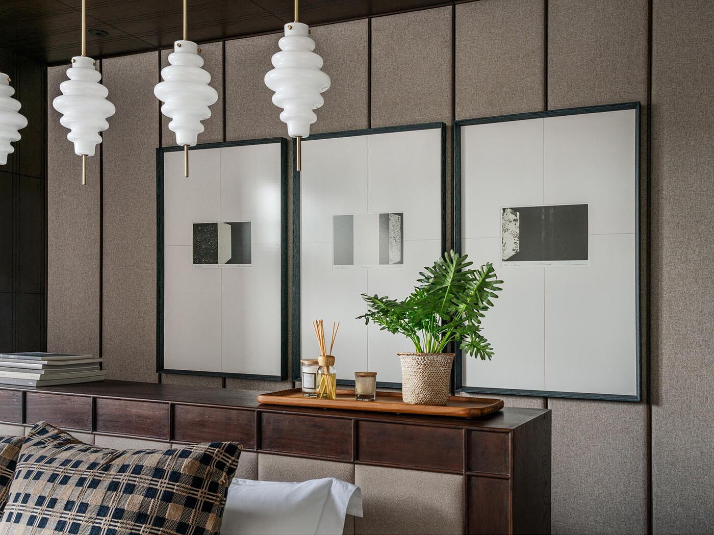 A minimalist bedroom with a central bed, pendant lighting, and layered artwork for a calm, balanced look.