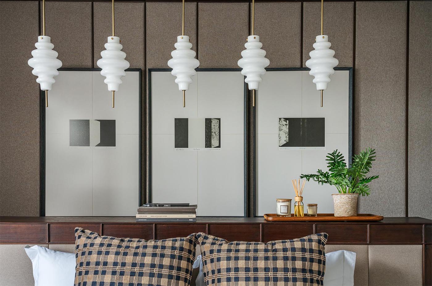 A minimalist bedroom with a central bed, pendant lighting, and layered artwork for a calm, balanced look.