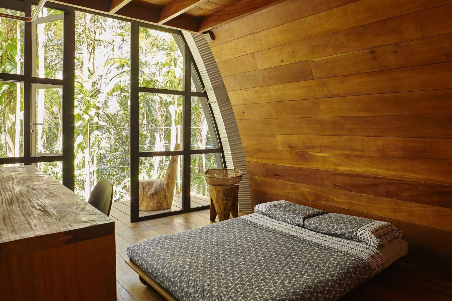 A cozy bedroom hidden behind a sliding barn door, with warm wood finishes and direct access to the outdoor deck.