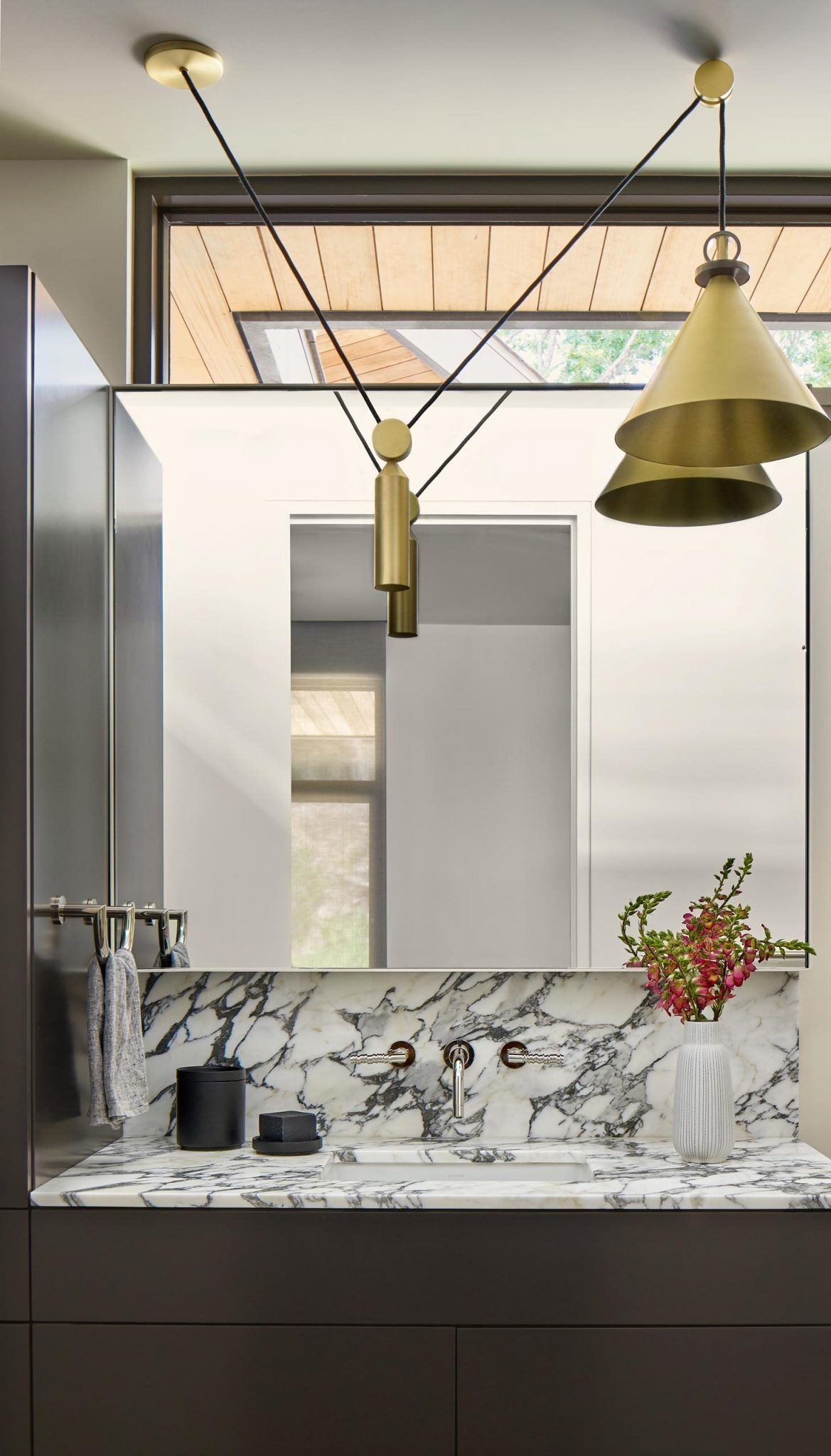 This bathroom pairs a dark vanity with a marbled surface and metallic lighting for contrast.