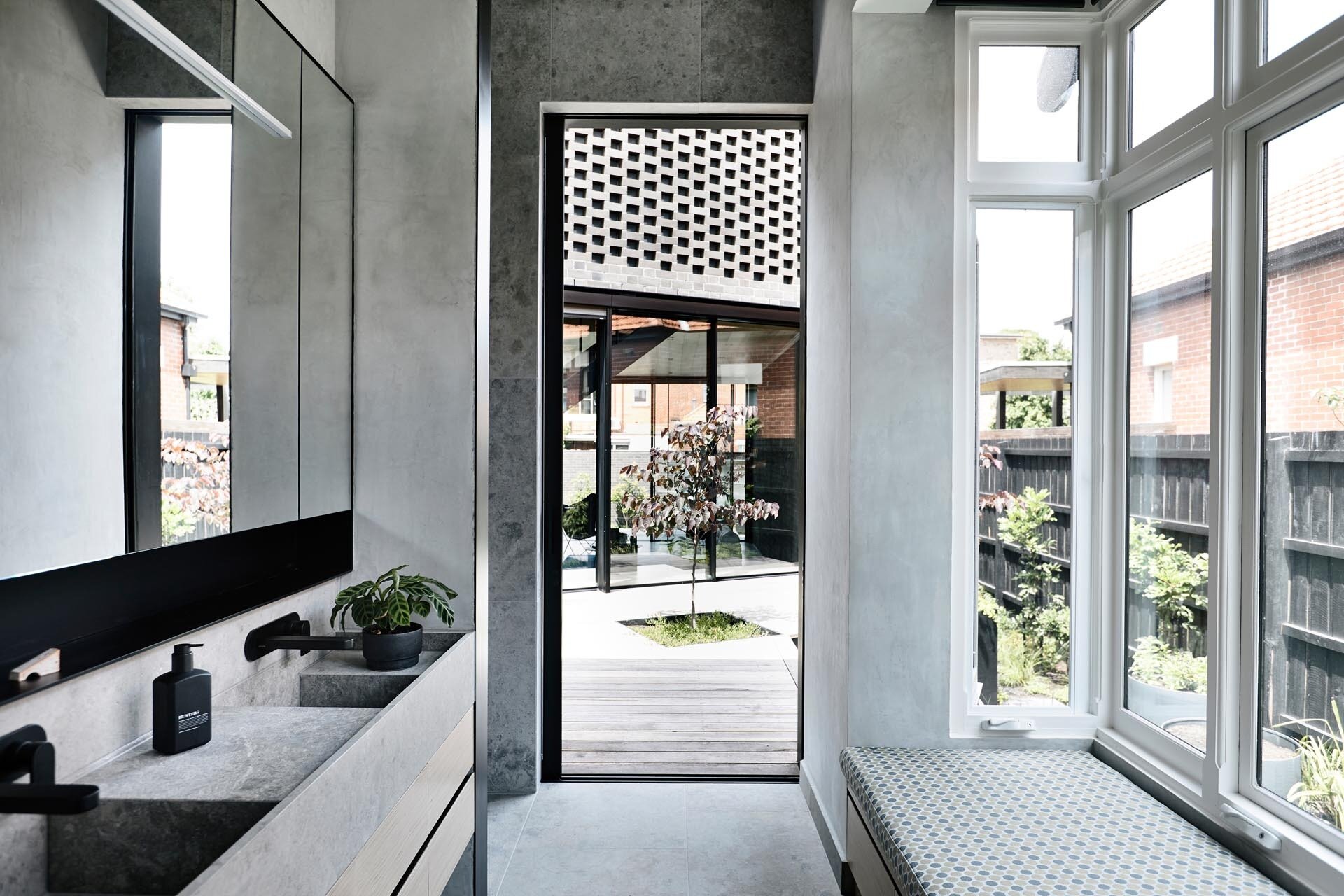 An ensuite bathroom opens to a courtyard, creating a seamless connection between indoor spaces and the outdoor area.