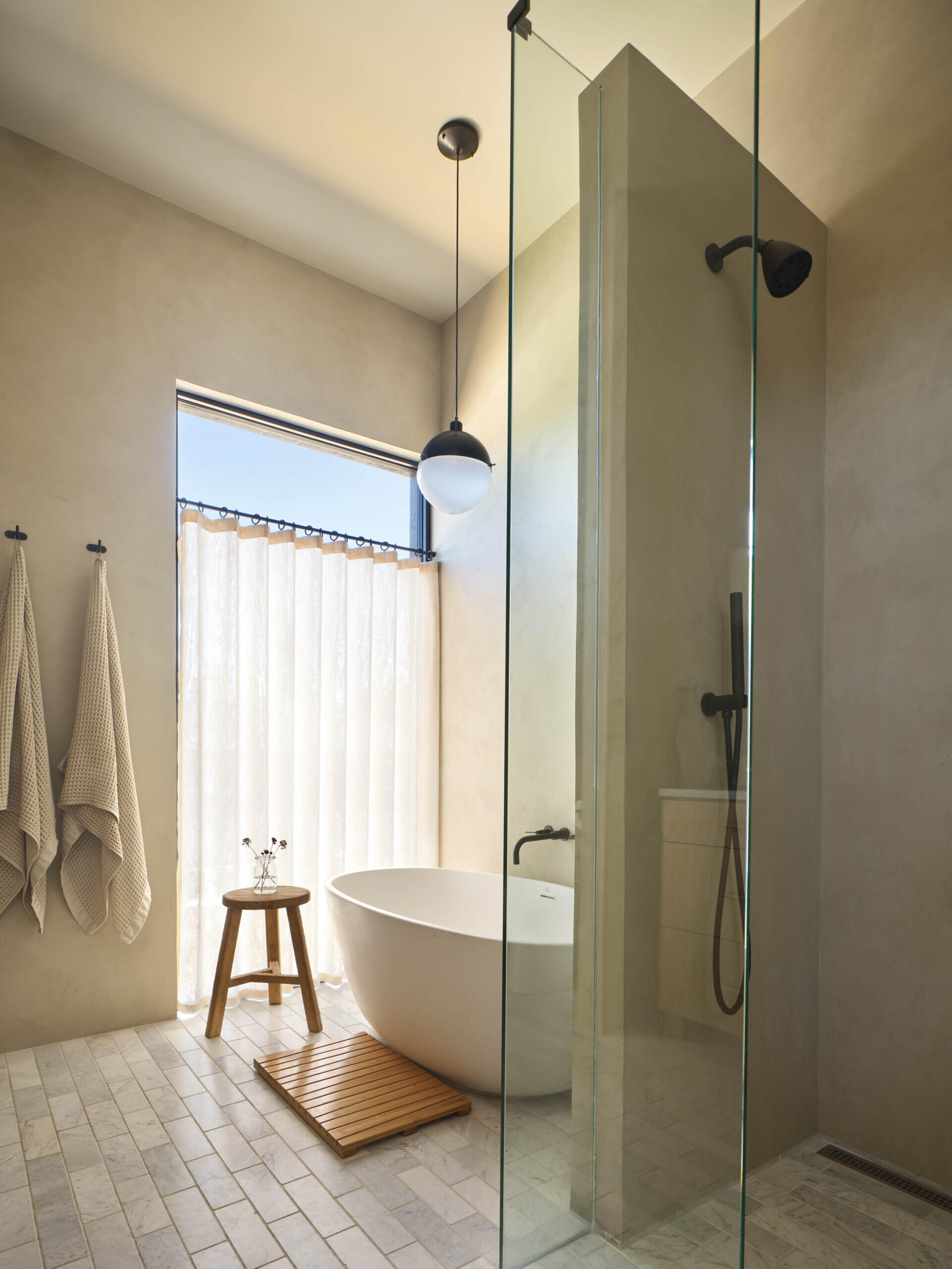 This bathroom leans into vertical space, with a higher ceiling that adds a sense of openness. A freestanding bathtub becomes the focal point, placed to take advantage of light and proportion.
