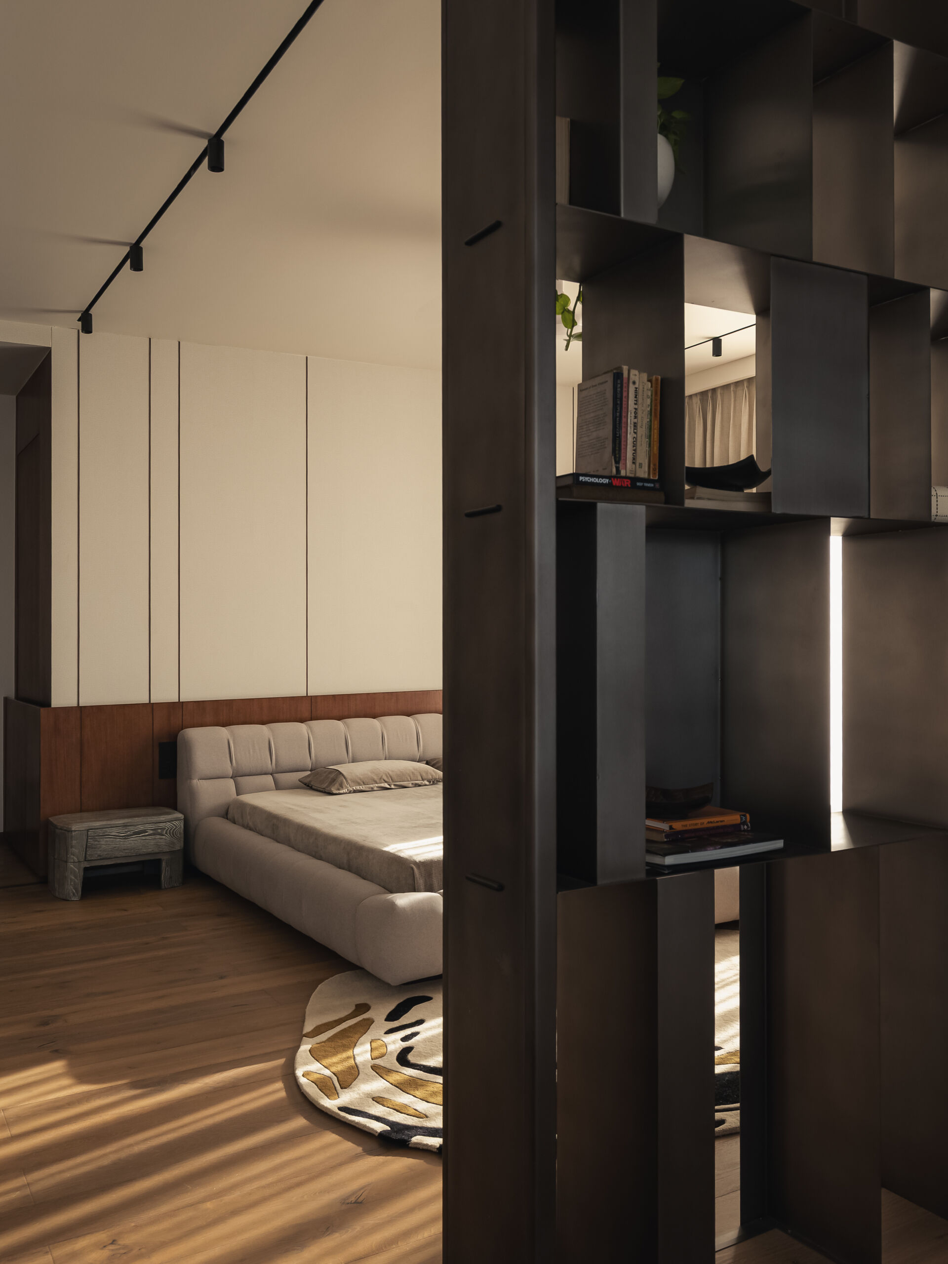 This primary bedroom, has a layered metal screen that transforms into a shelving unit at the entrance, creating a feature that will eventually hold travel memories and personal objects.