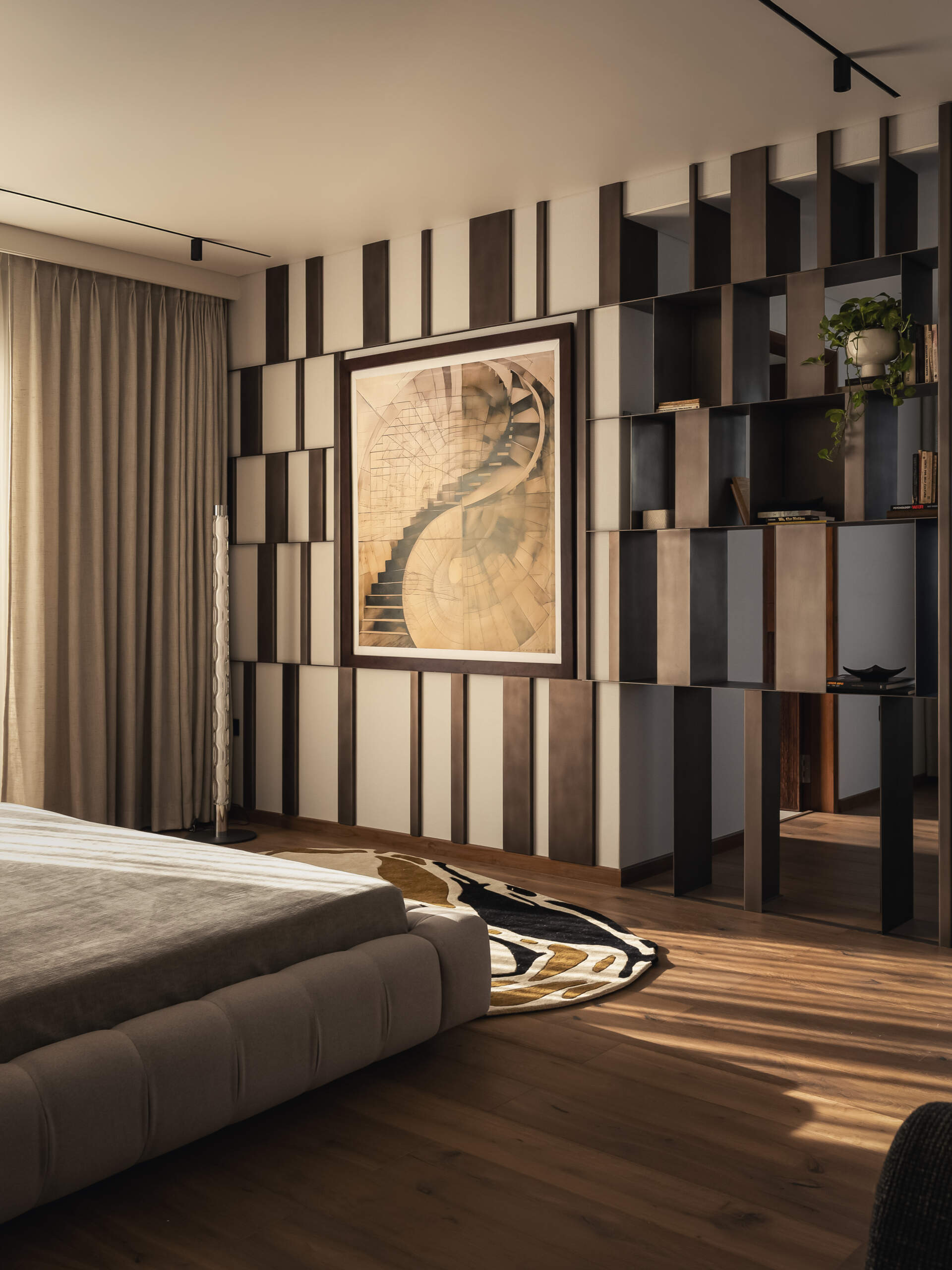 This primary bedroom, has a layered metal screen that transforms into a shelving unit at the entrance, creating a feature that will eventually hold travel memories and personal objects.