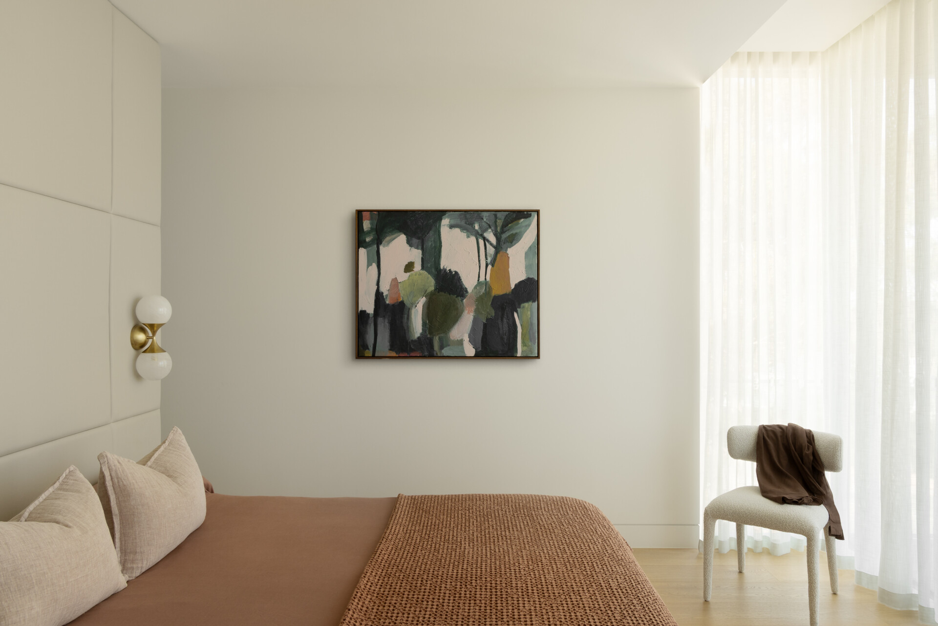 The bedrooms continue the home’s focus on light and simplicity. Openings are positioned to capture views of surrounding greenery, keeping each space calm and connected to the outdoors. The material palette remains calm with neutral tones, and a pop of muted color is added with the inclusion of artwork.