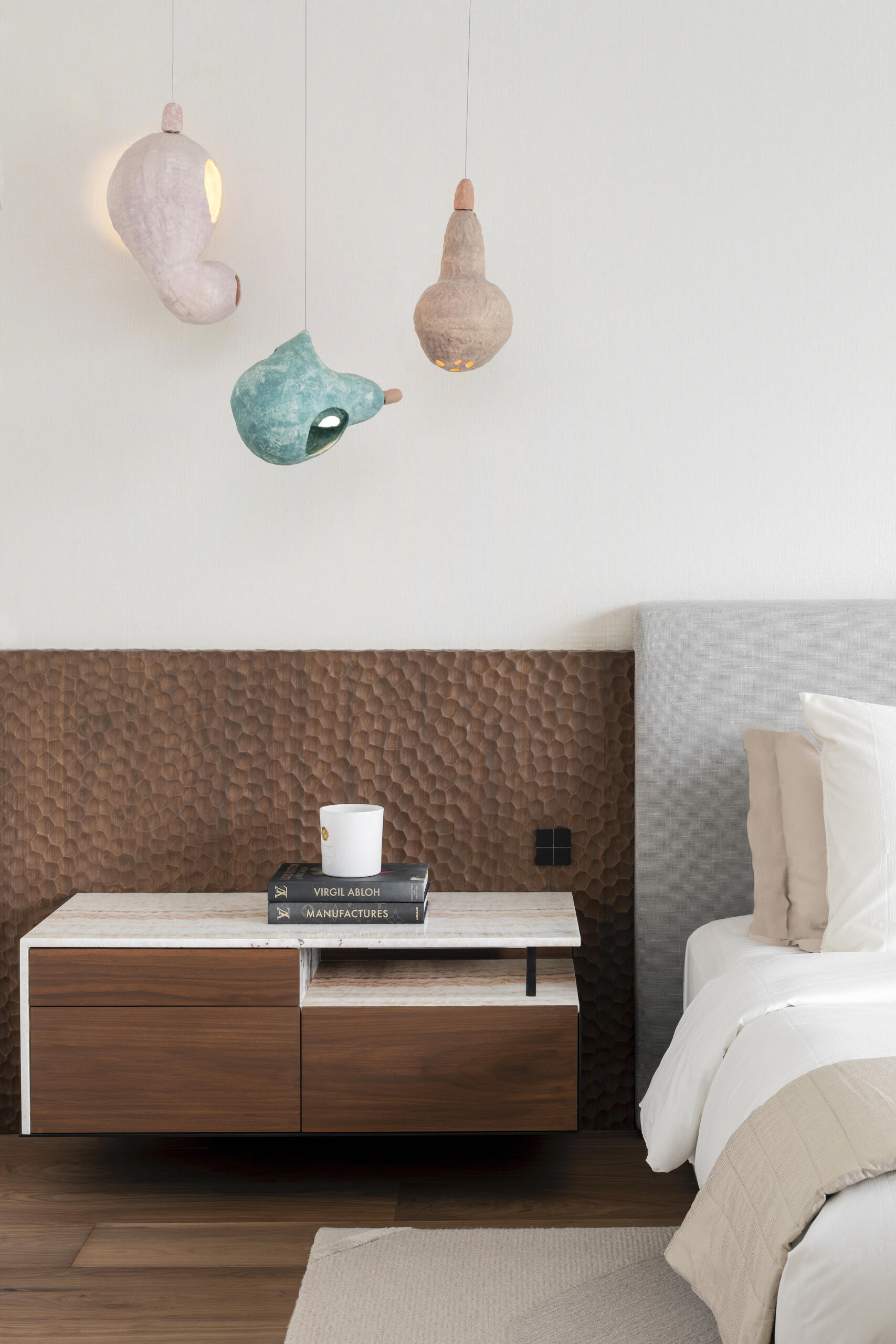 In the main bedroom, the tone shifts. The palette becomes more muted, and the forms are simplified. The focus moves toward comfort, with softer textures and a more restrained use of color. Even so, the sculptural influence remains, visible in the choice of furniture and lighting.