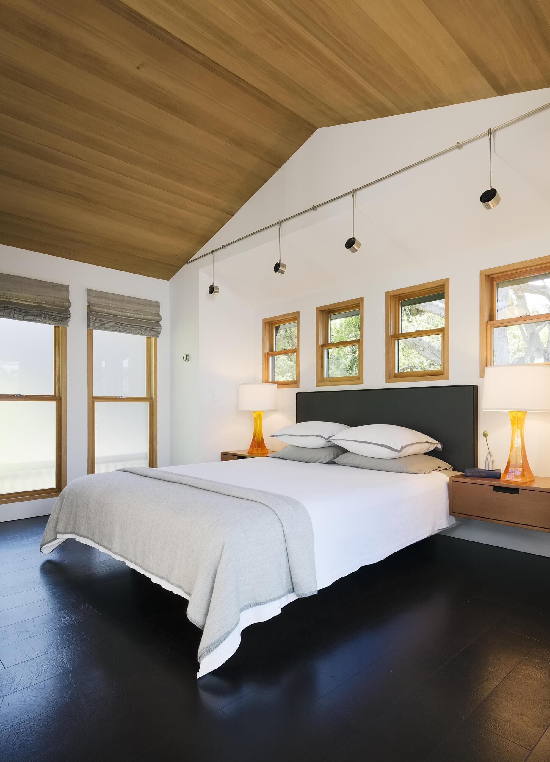 The main bedroom shifts into a more tactile palette. A clear Western red cedar ceiling brings warmth overhead, while the leather flooring adds a softer, unexpected finish underfoot.