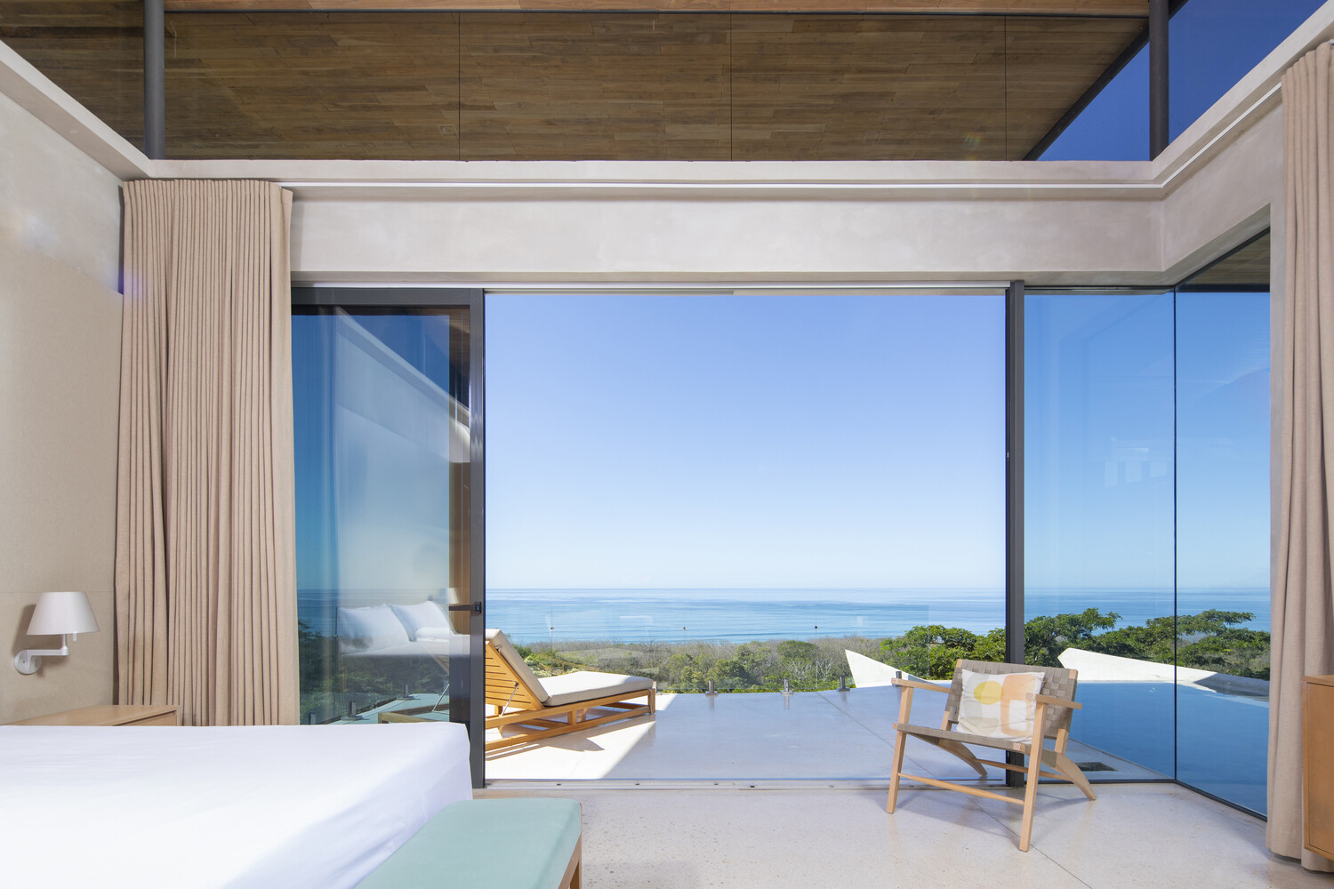 A primary bedroom with direct outdoor access, positioned beside the pool and open to the surrounding landscape.