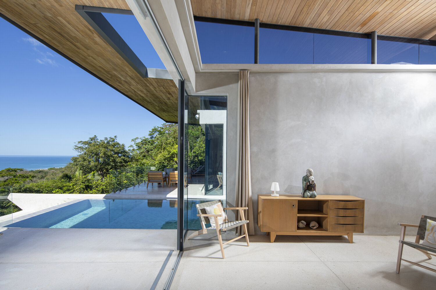 A primary bedroom with direct outdoor access, positioned beside the pool and open to the surrounding landscape.