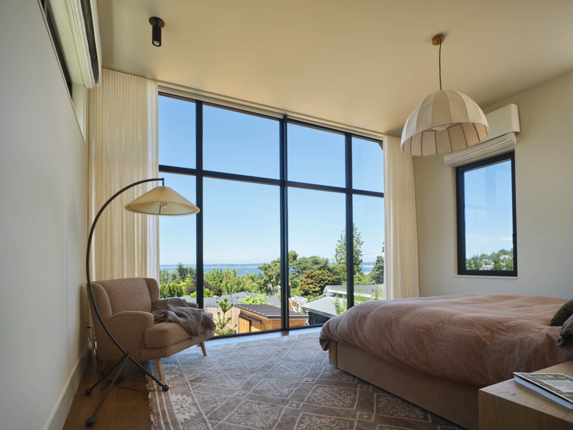 This primary suite takes full advantage of the home’s elevated position. Large windows frame views out toward the bay, bringing in light throughout the day.