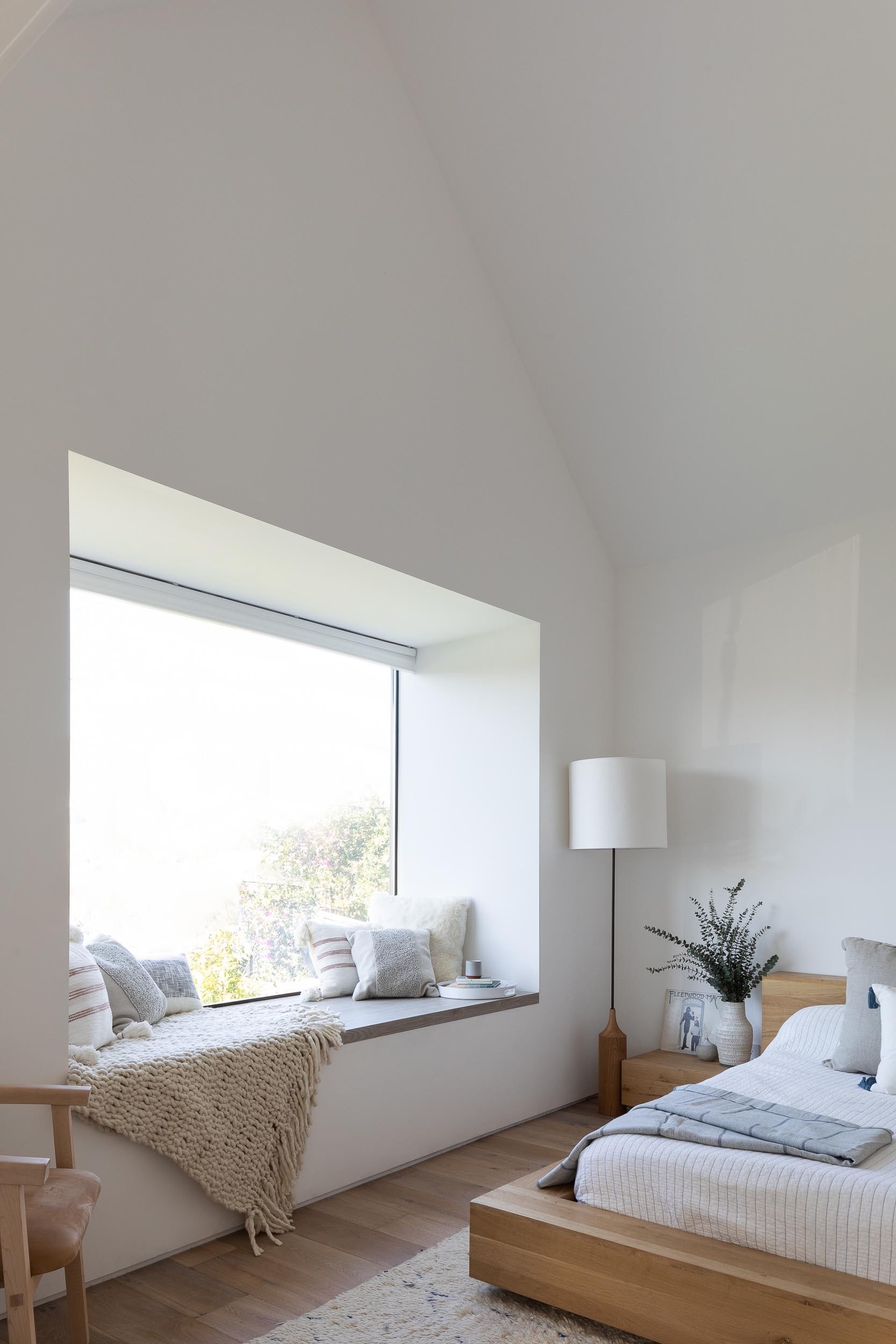 A vaulted ceiling, skylight, and window seat make this modern bedroom feel open, bright, and inviting.