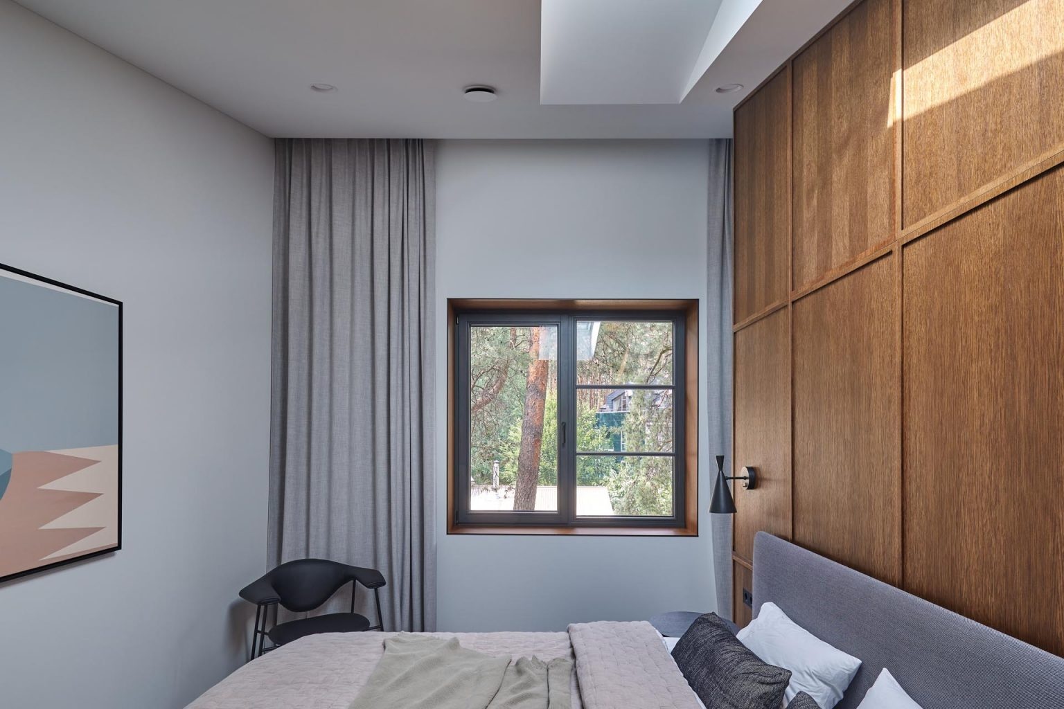 A wood accent wall meets dark cabinetry and soft textiles in this calm, modern bedroom.