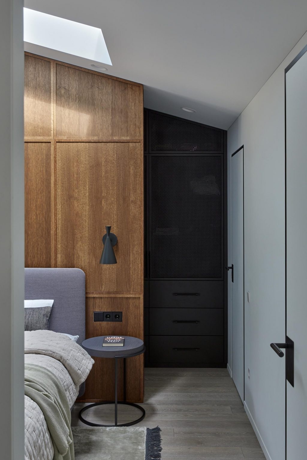 A wood accent wall meets dark cabinetry and soft textiles in this calm, modern bedroom.