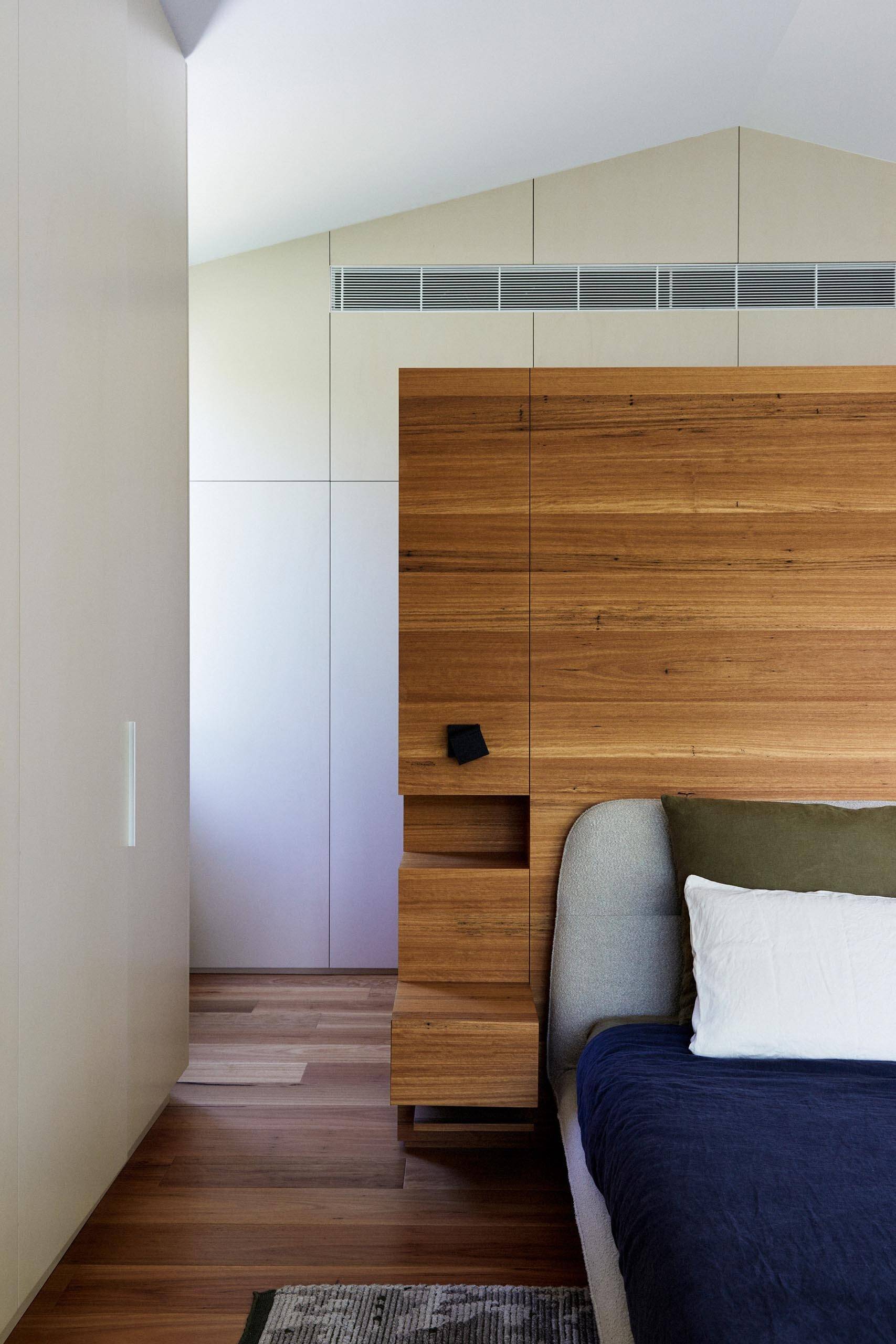 In this bathroom, a partial wood wall forms the backdrop to the bed, integrating bedside tables and shelving into a single feature.