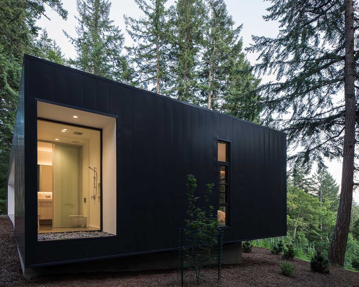 Black metal and white stucco create a striking modern exterior for this Orcas Island home, set against forest views.