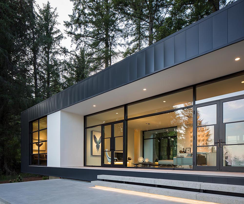 Black-framed doors open to a concrete terrace with a built-in fire pit, perfect for outdoor living.