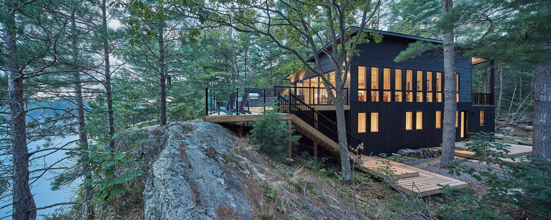Black wood siding and matching window frames give this Muskoka cottage a bold yet subtle exterior that blends into the forest.