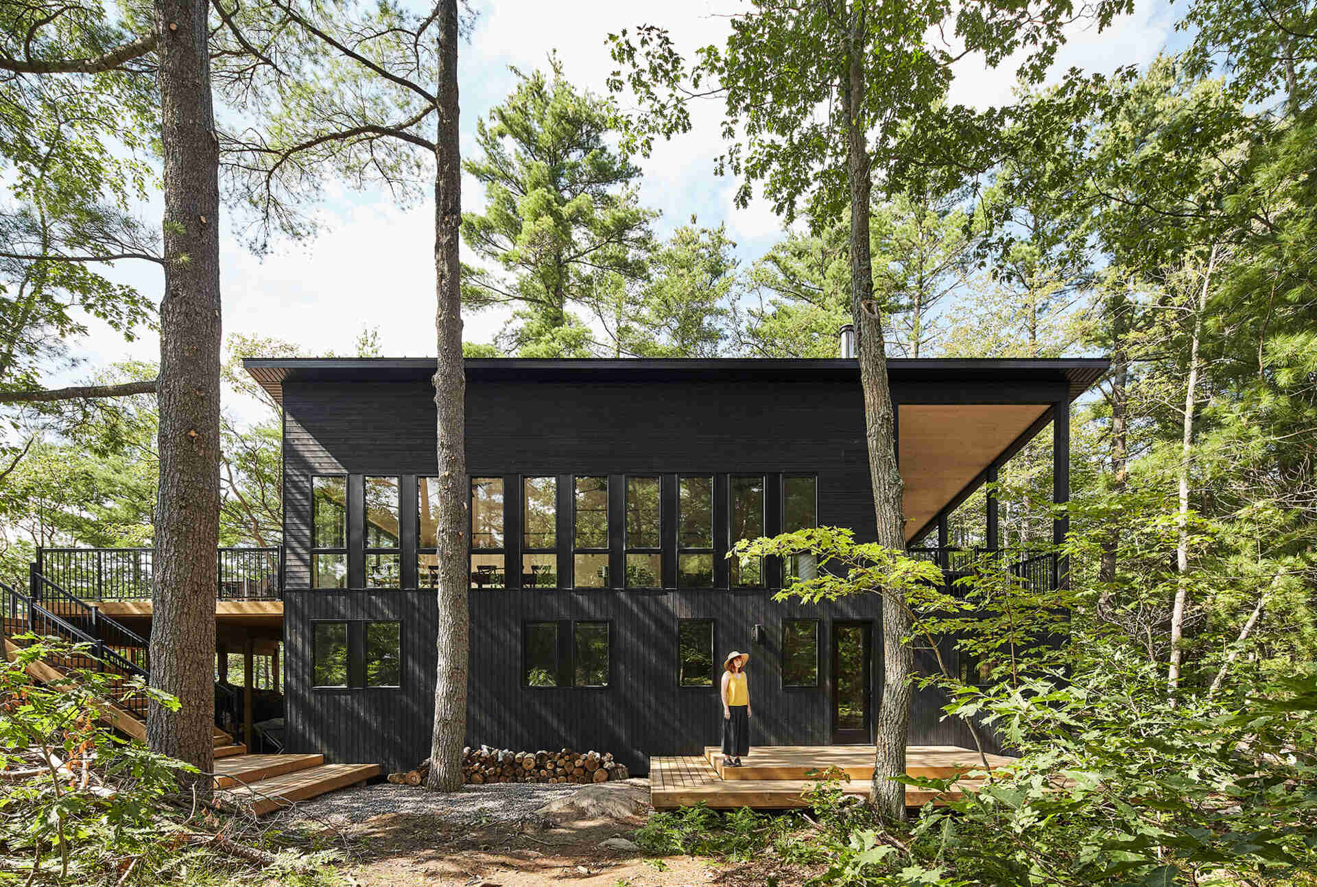 Black wood siding and matching window frames give this Muskoka cottage a bold yet subtle exterior that blends into the forest.