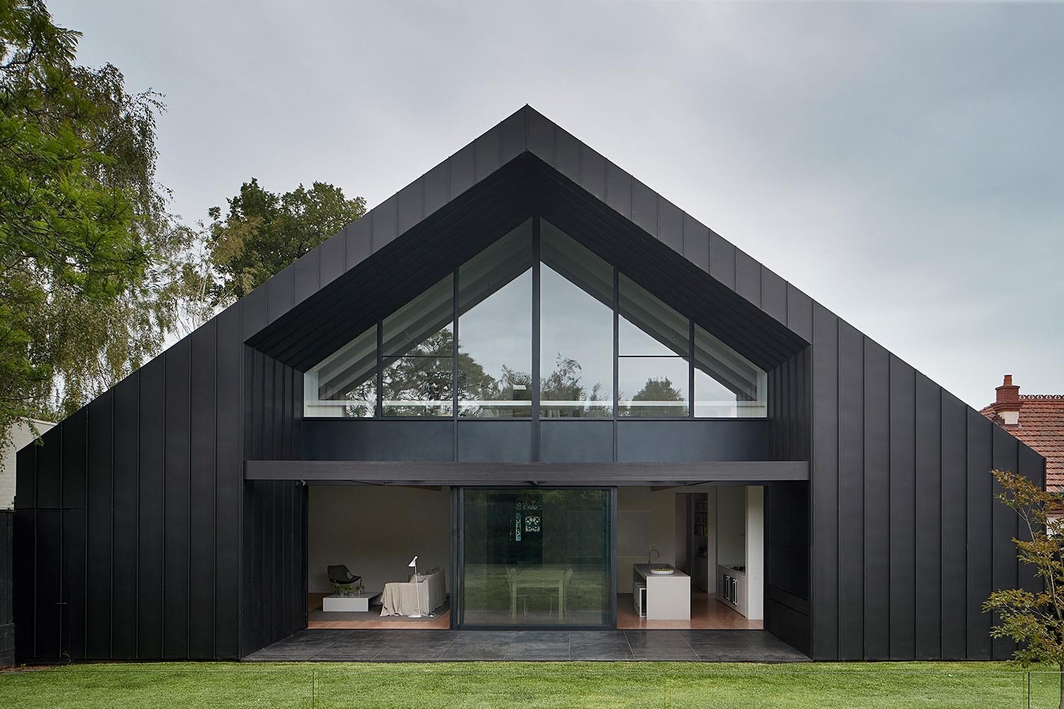 A striking black exterior contrasts with lush greenery, giving the modern addition a bold and clean look.
