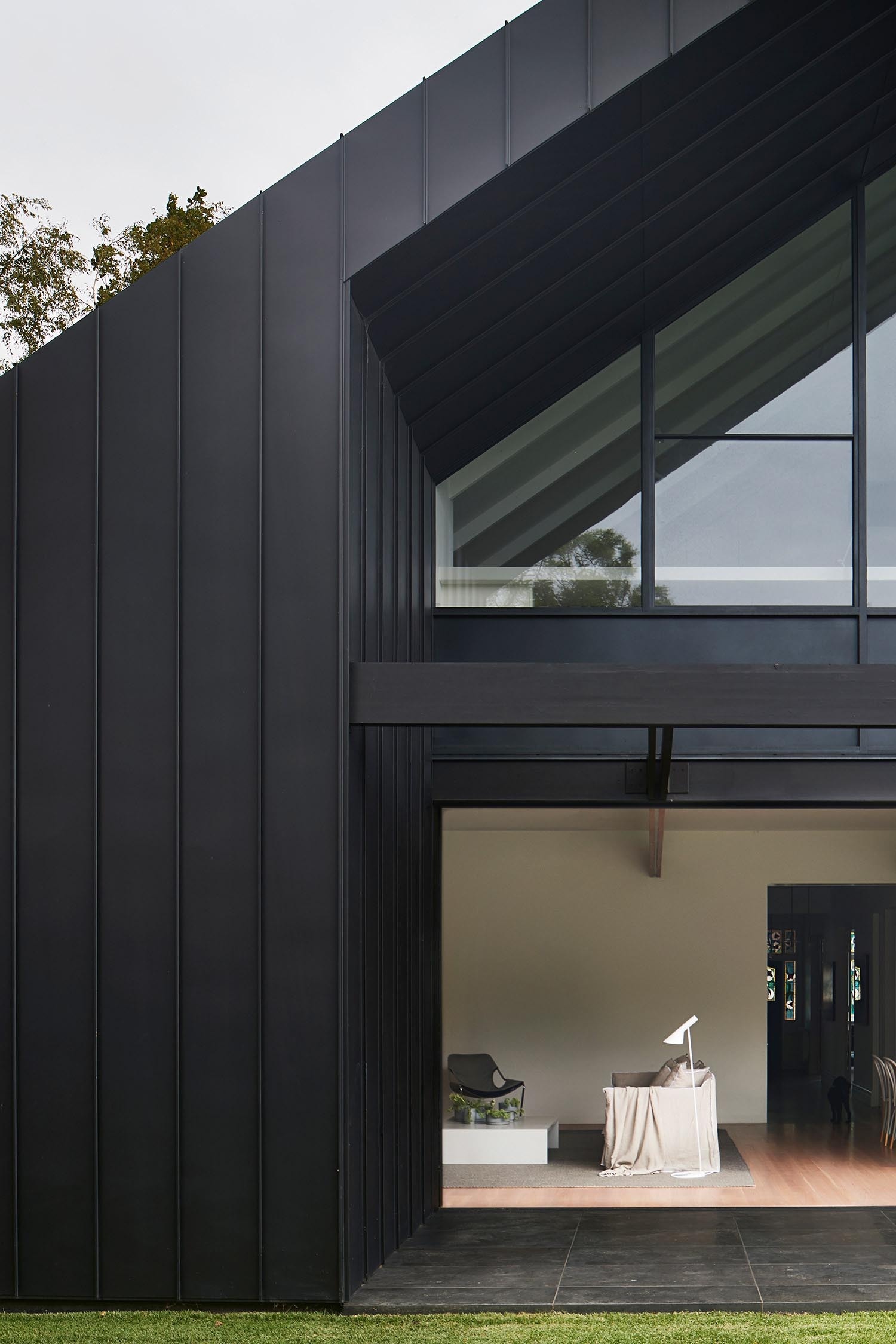 A striking black exterior contrasts with lush greenery, giving the modern addition a bold and clean look.