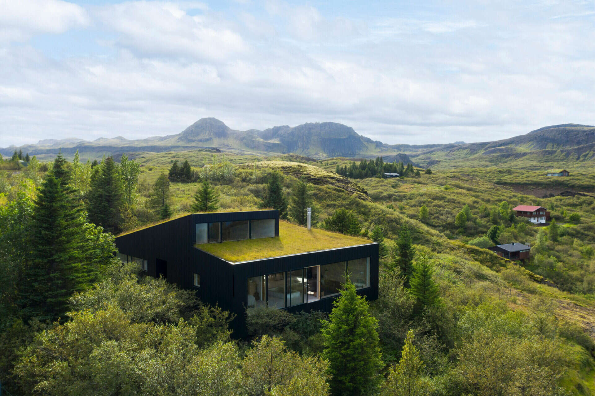 A hillside home in Iceland designed with staggered concrete levels that step with the landscape, creating a low-profile architectural form.