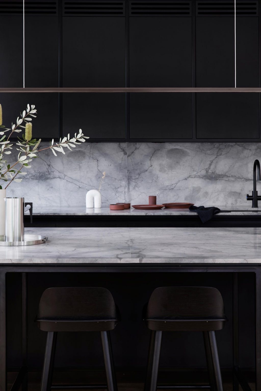 Matte black Paperock cabinets, grey marble, and minimalist lighting define this sleek, modern kitchen.