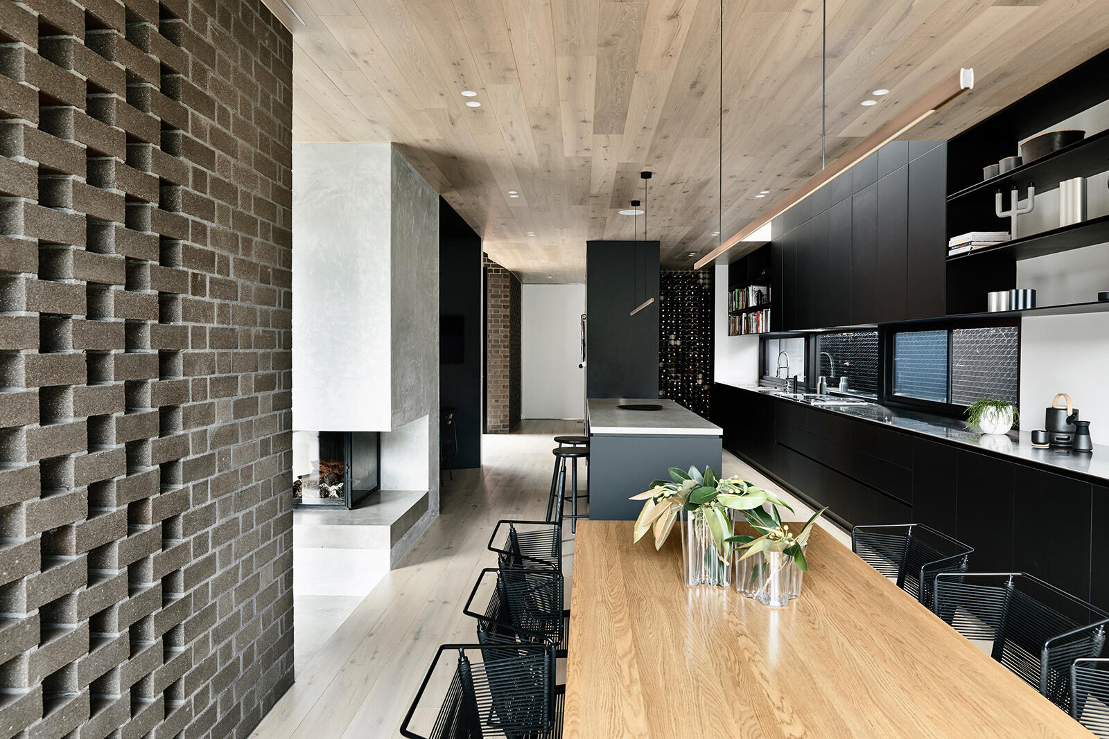 Matte black kitchen cabinets create a bold statement in this open-plan dining and kitchen space, adding contrast and clean lines.