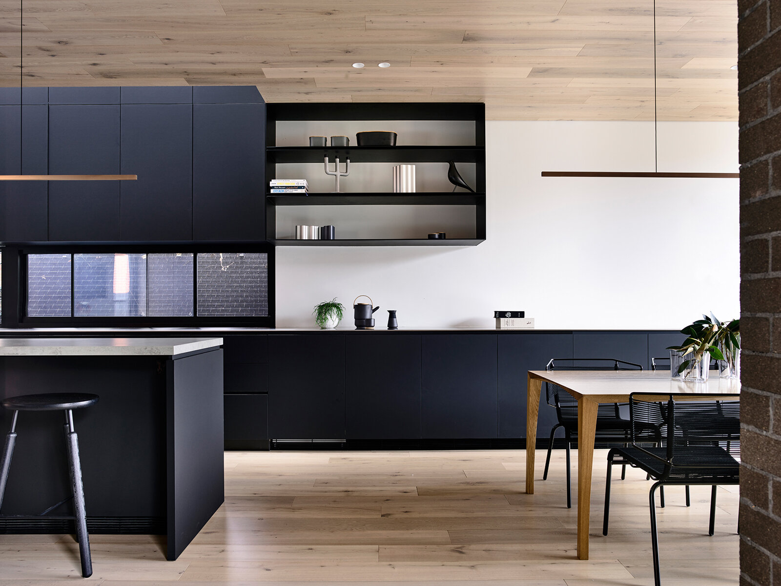 Matte black kitchen cabinets create a bold statement in this open-plan dining and kitchen space, adding contrast and clean lines.