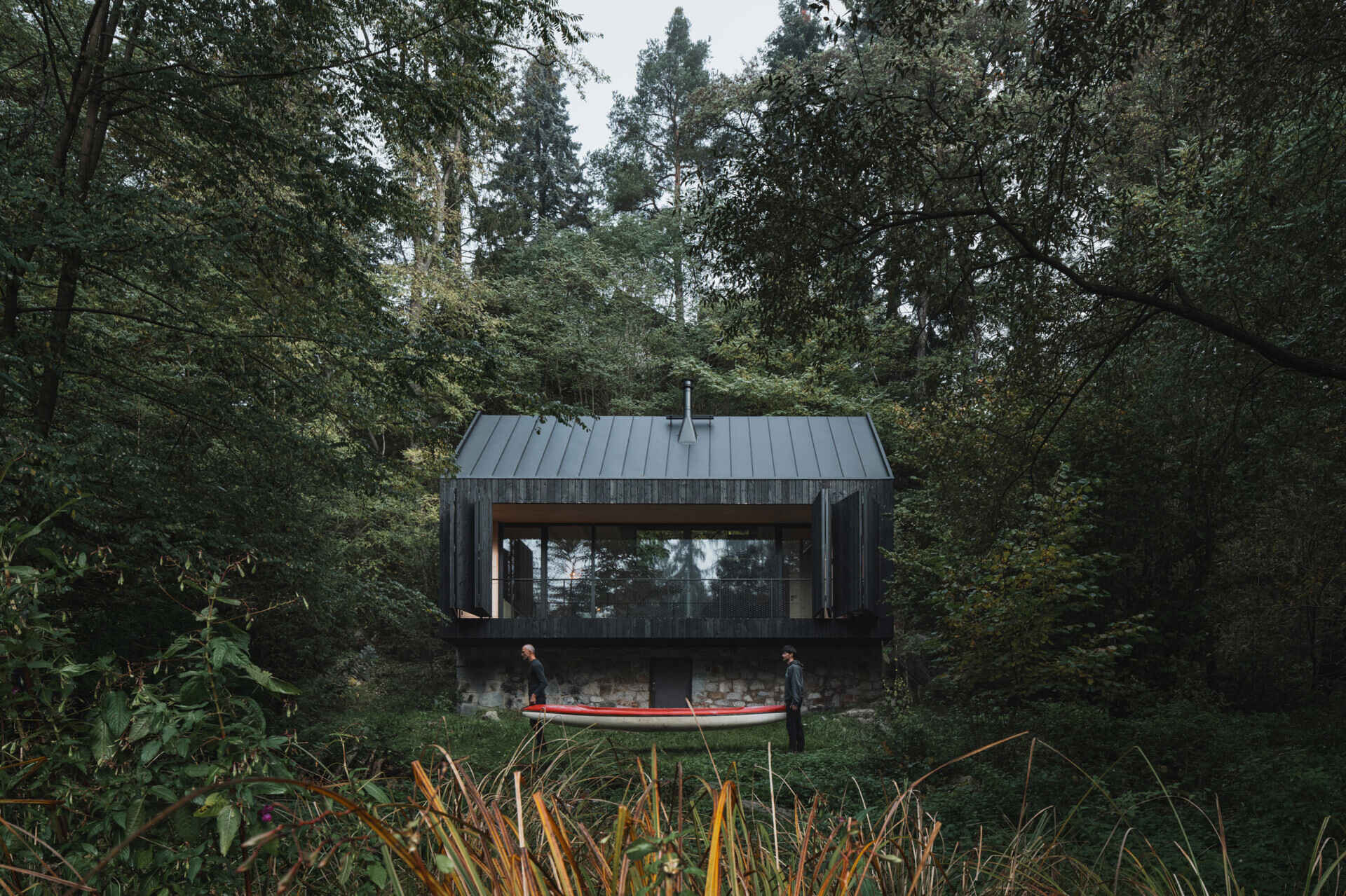 A small cabin in Prosecnice, Czech Republic rebuilt on its original stone base, opening up to peaceful views over the Sázava River.