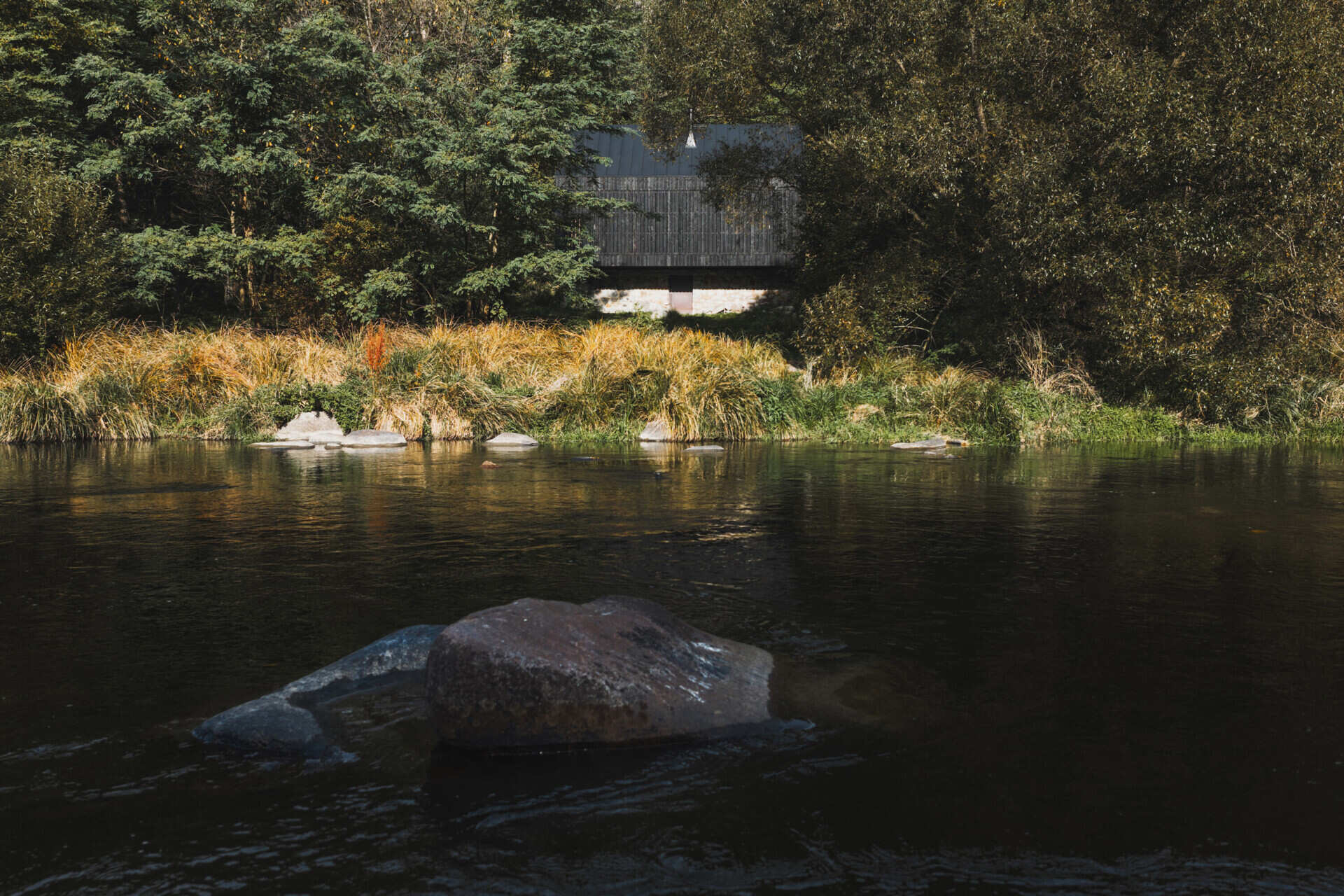 A small cabin in Prosecnice, Czech Republic rebuilt on its original stone base, opening up to peaceful views over the Sázava River.