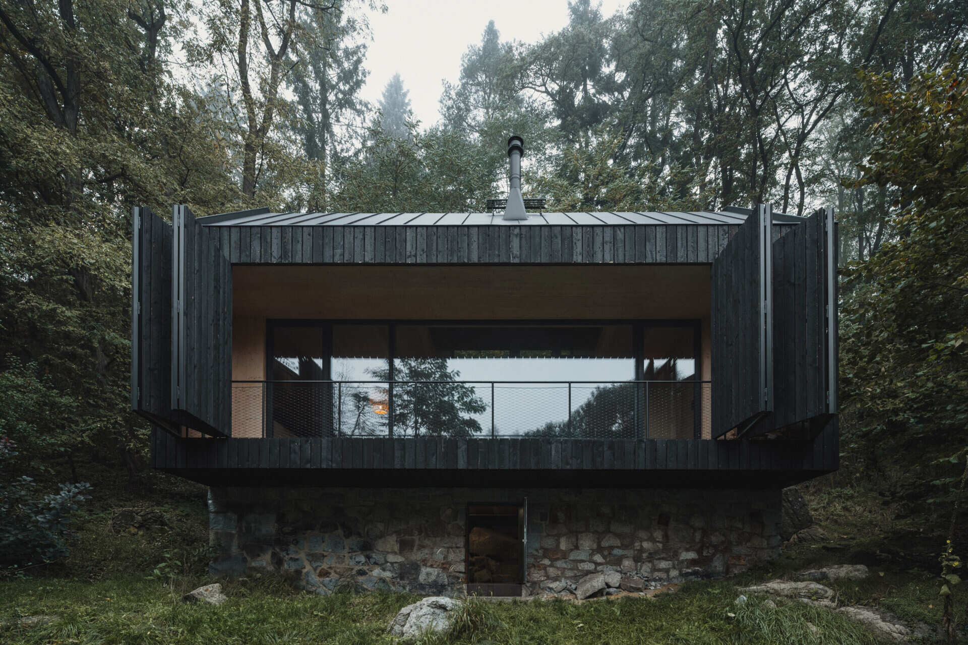 A small cabin in Prosecnice, Czech Republic rebuilt on its original stone base, opening up to peaceful views over the Sázava River.