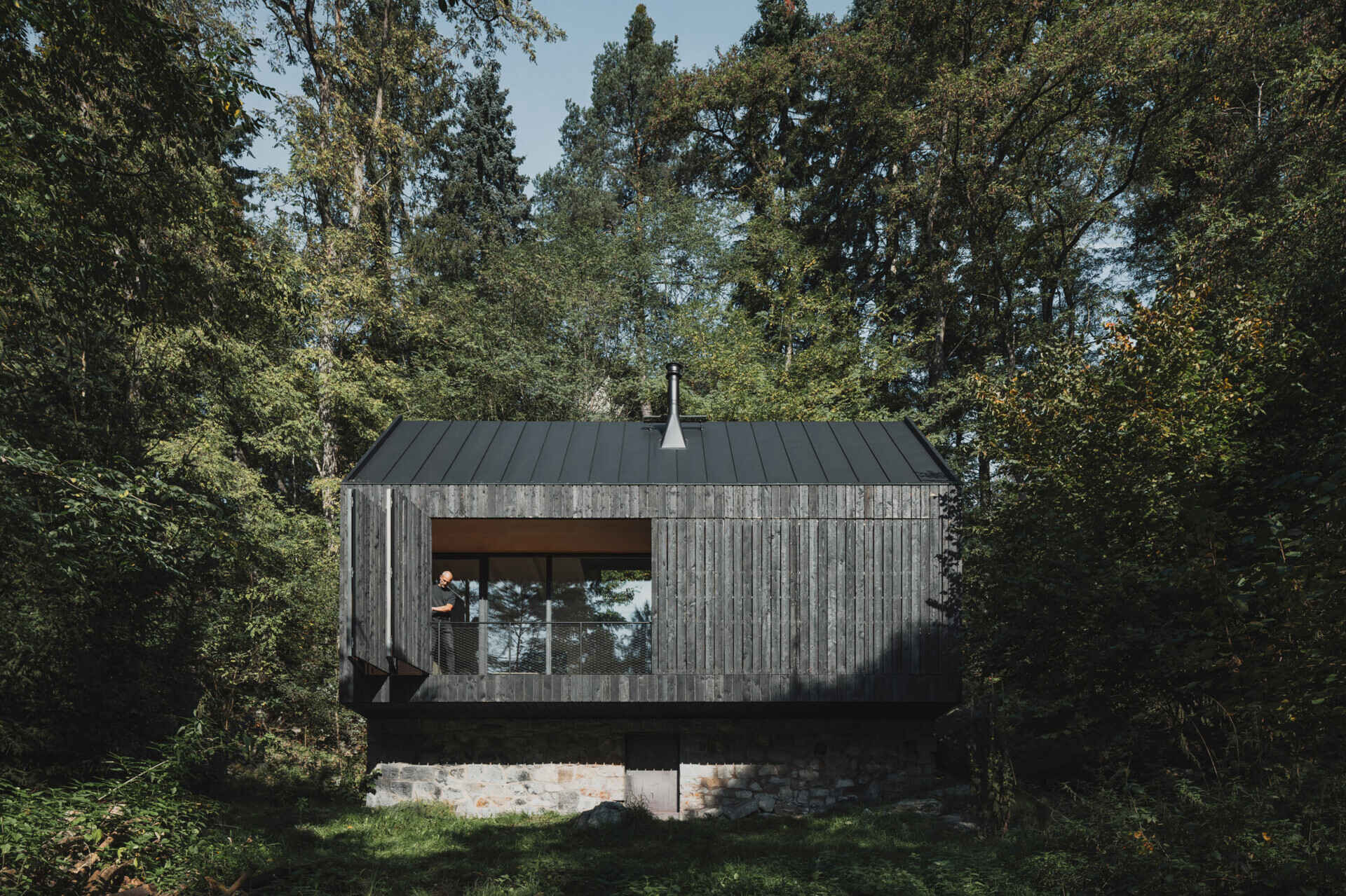 A small cabin in Prosecnice, Czech Republic rebuilt on its original stone base, opening up to peaceful views over the Sázava River.