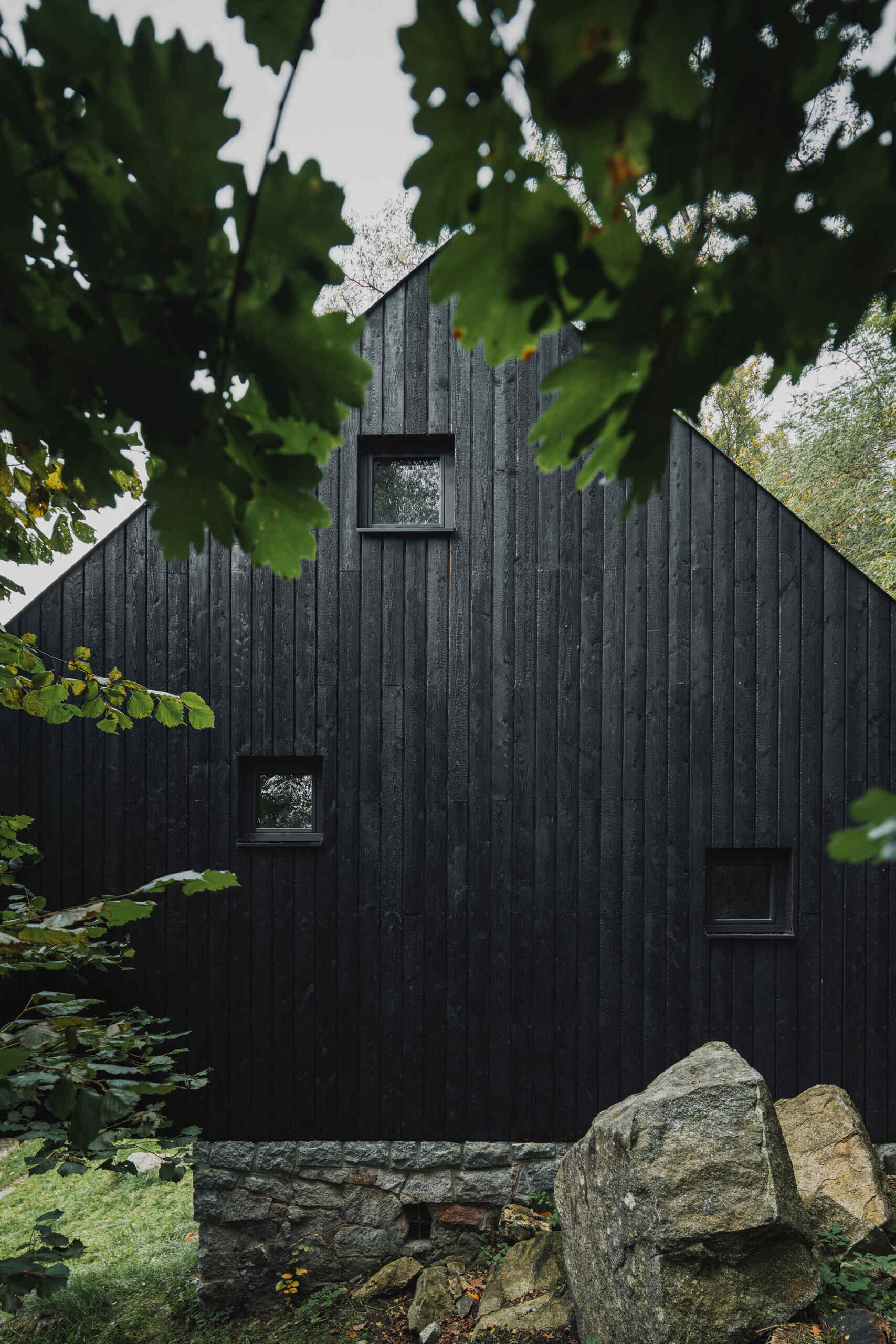 A small cabin in Prosecnice, Czech Republic rebuilt on its original stone base, opening up to peaceful views over the Sázava River.