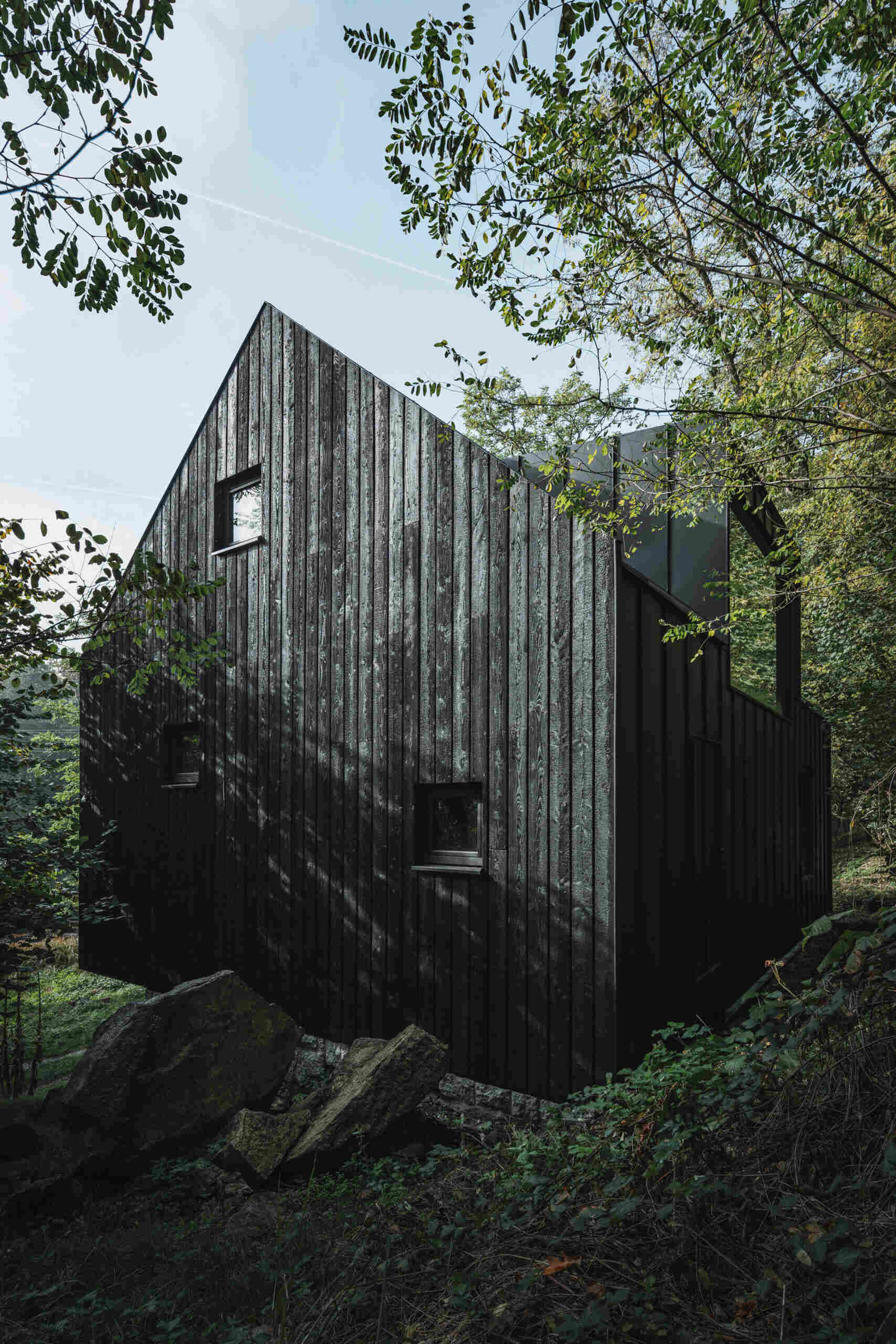 Charred larch cladding and folding shutters give this cabin a bold exterior that can fully open to the river or close into a secure box.