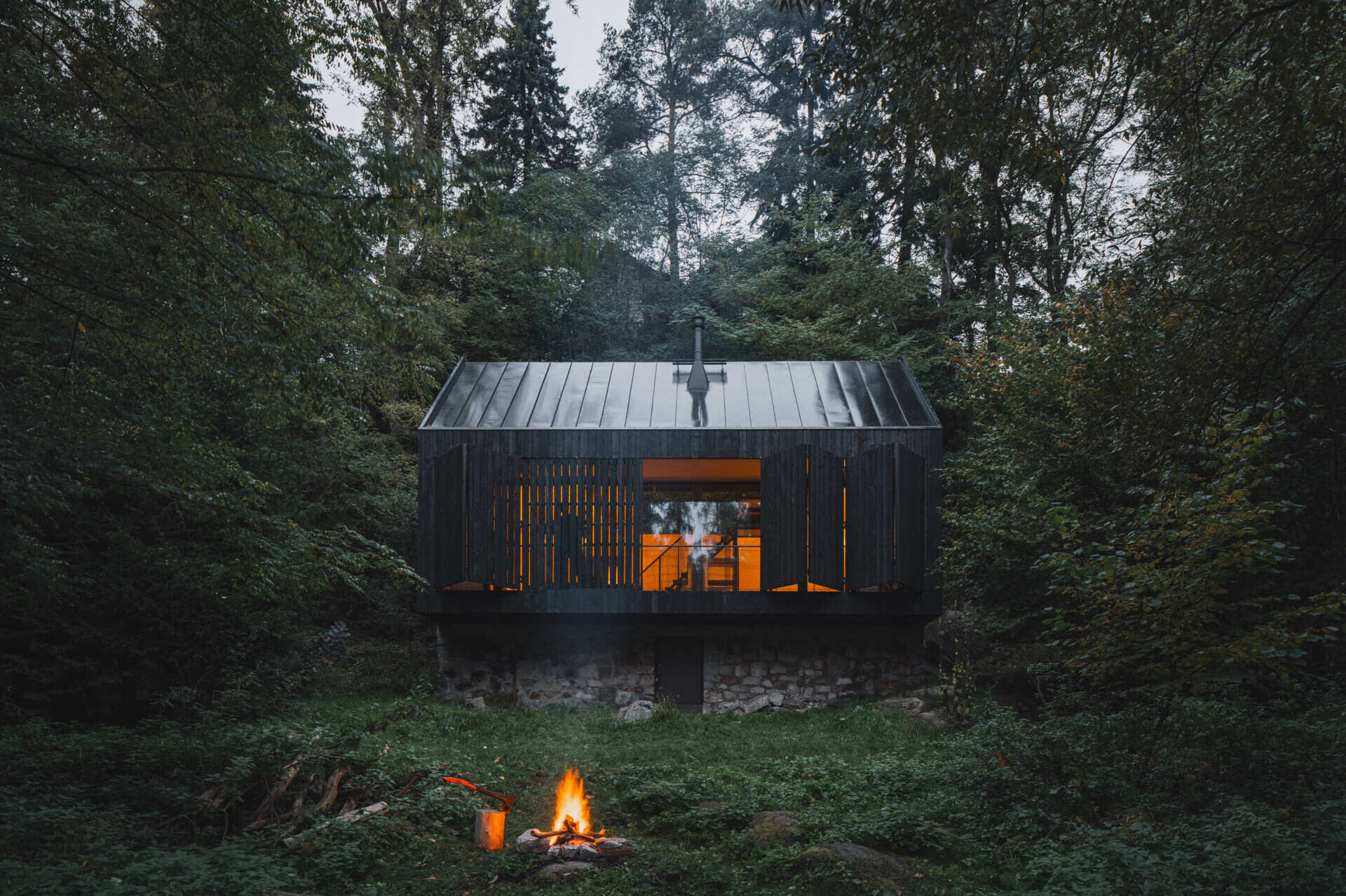 Charred larch cladding and folding shutters give this cabin a bold exterior that can fully open to the river or close into a secure box.