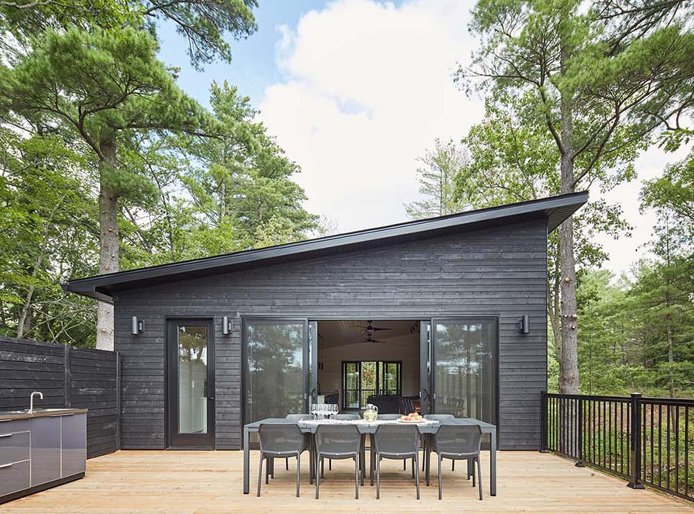 Two outdoor dining areas, including a lake-facing deck and covered space, create flexible entertaining zones for this Muskoka cottage.