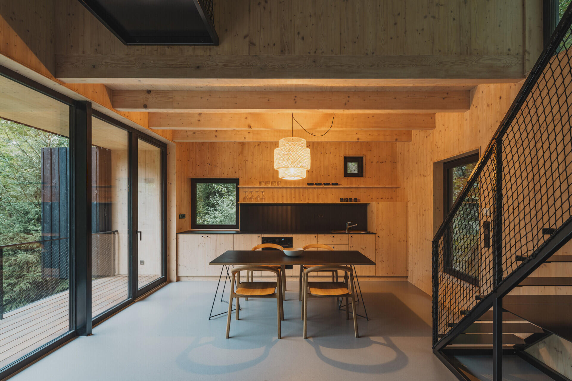In this cabin, a full-height living space with floor-to-ceiling glazing connects seamlessly to a raised terrace overlooking the river.