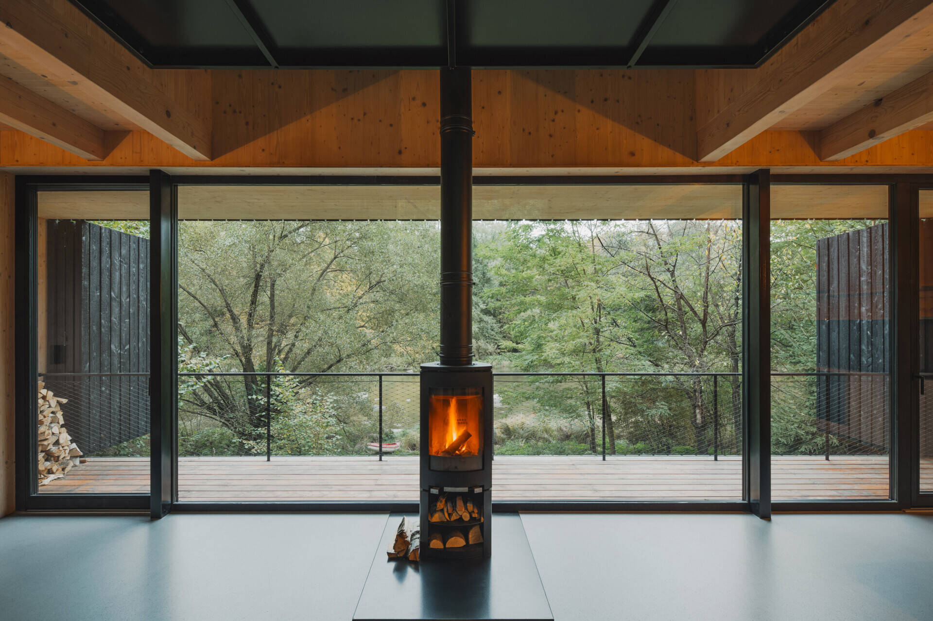 In this cabin, a full-height living space with floor-to-ceiling glazing connects seamlessly to a raised terrace overlooking the river.