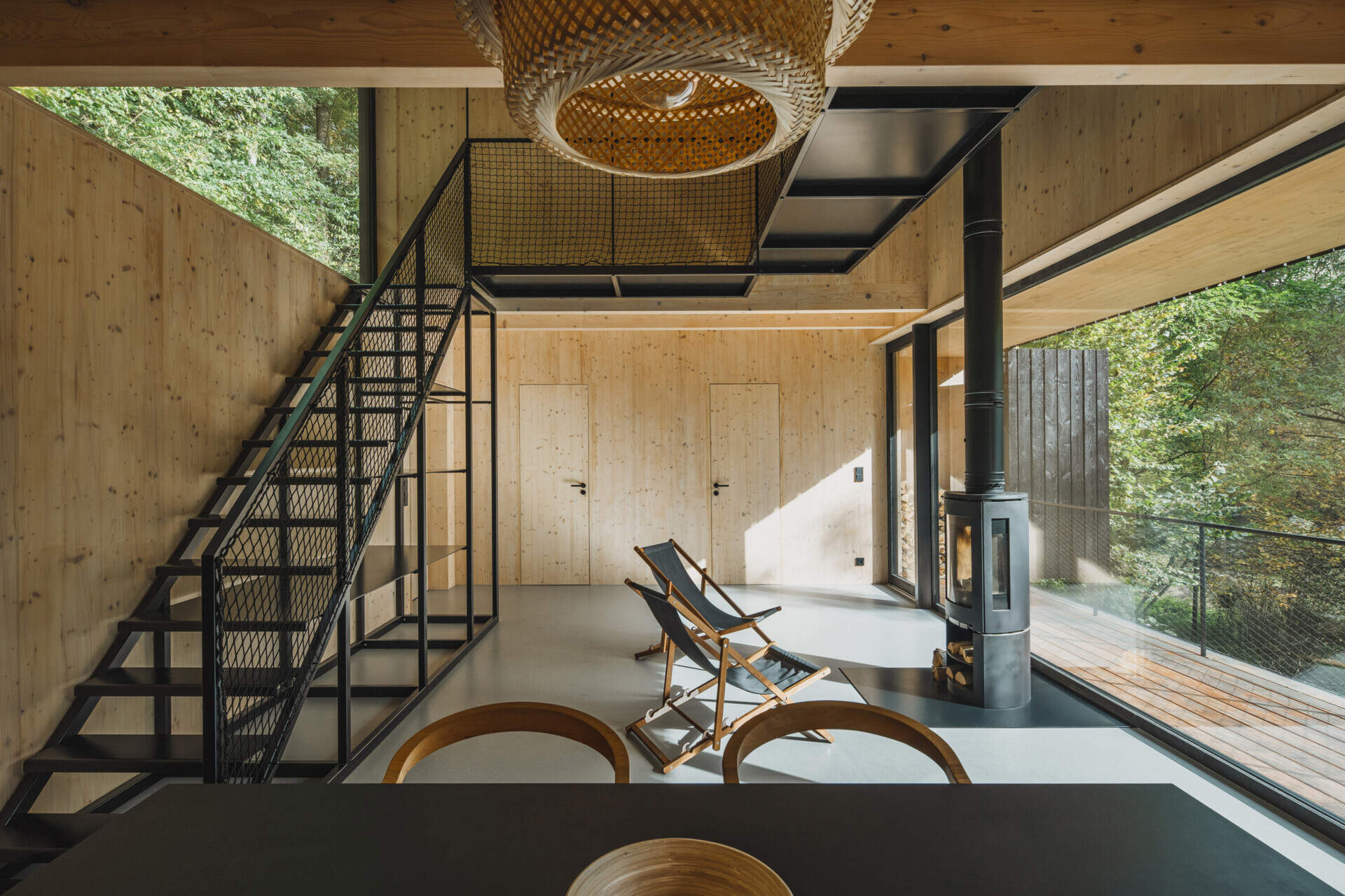 A full-height living space with floor-to-ceiling glazing connects seamlessly to a raised terrace overlooking the river.