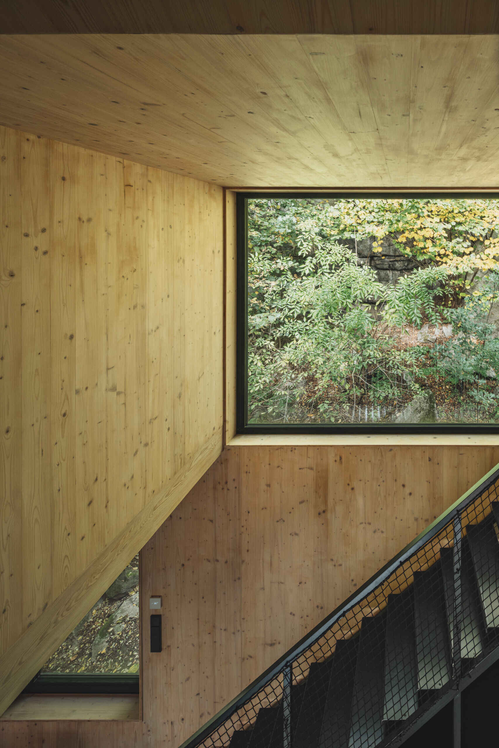 Compact attic sleeping spaces in this cabin sit above the open living area, offering a quiet shift in perspective toward the surrounding cliffs.