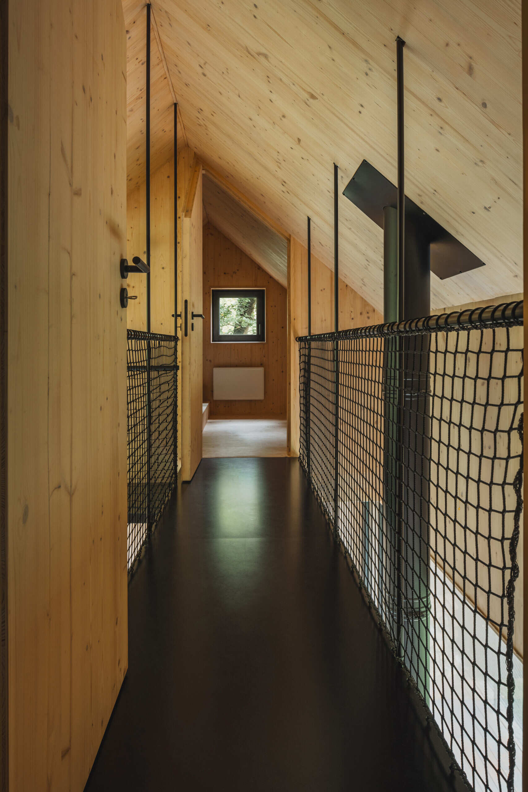 Compact attic sleeping spaces in this cabin sit above the open living area, offering a quiet shift in perspective toward the surrounding cliffs.