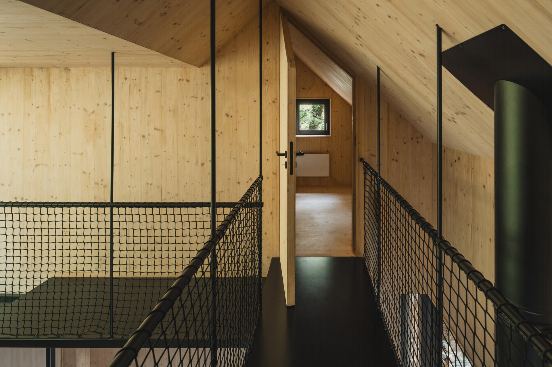 Compact attic sleeping spaces in this cabin sit above the open living area, offering a quiet shift in perspective toward the surrounding cliffs.