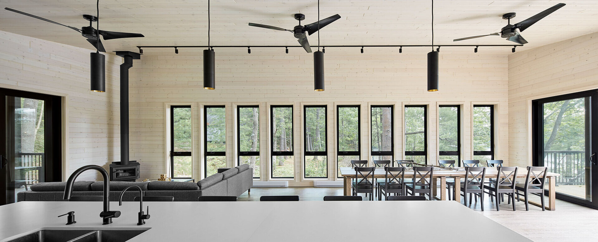 An open-plan upper level with a fireplace lounge, multiple dining tables, and a bold black-and-white kitchen designed for large family gatherings.