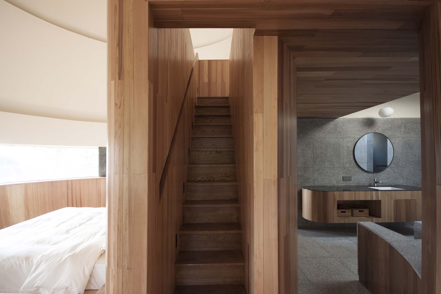 A horizontal window and circular skylight bring natural light into the bathroom while maintaining privacy from outside paths.